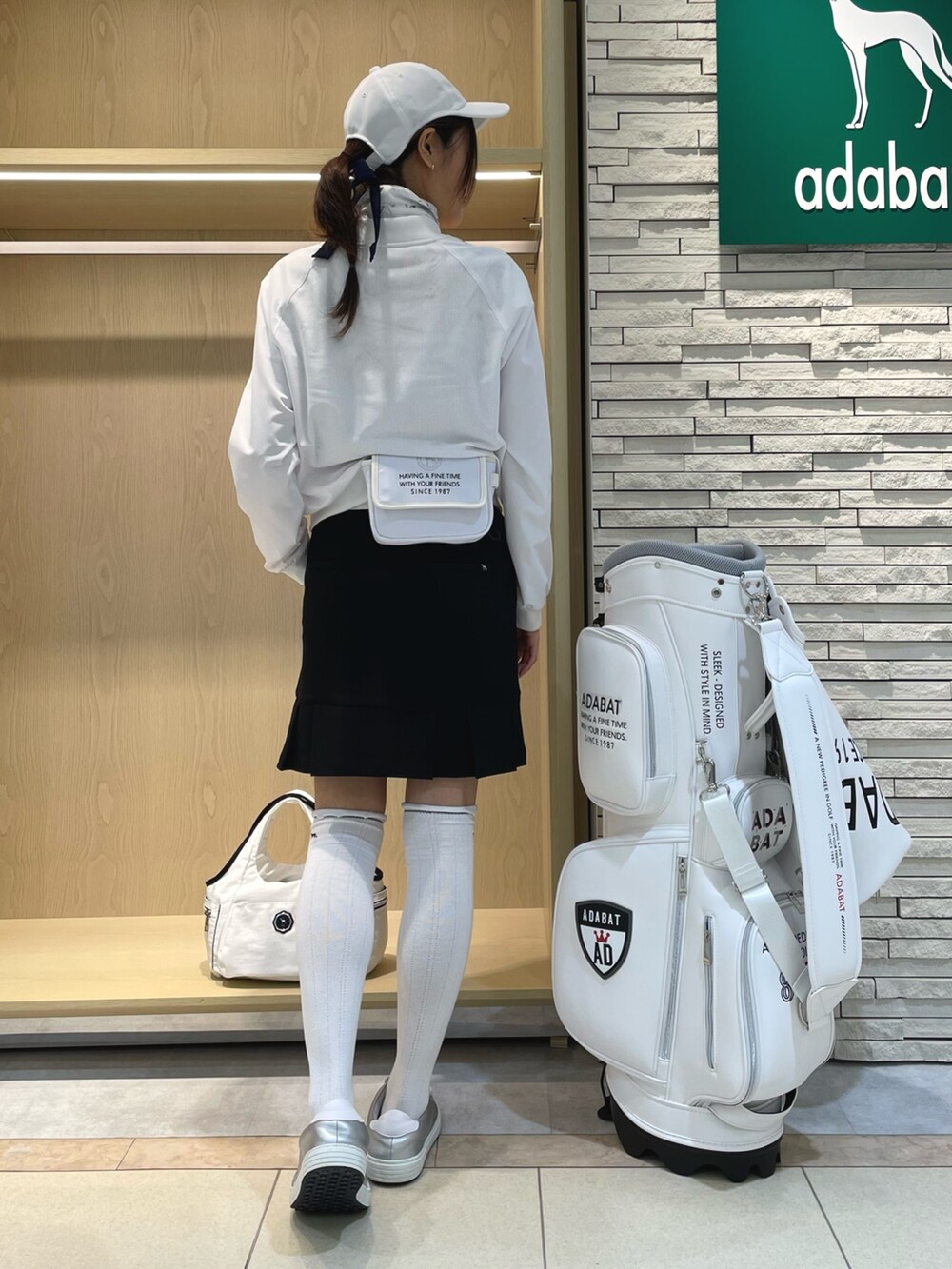 ホワイト系のブルゾン、ホワイト系のポロシャツ、ホワイト系のトートバッグを着用したレディースの春コーディネートの2枚目の写真