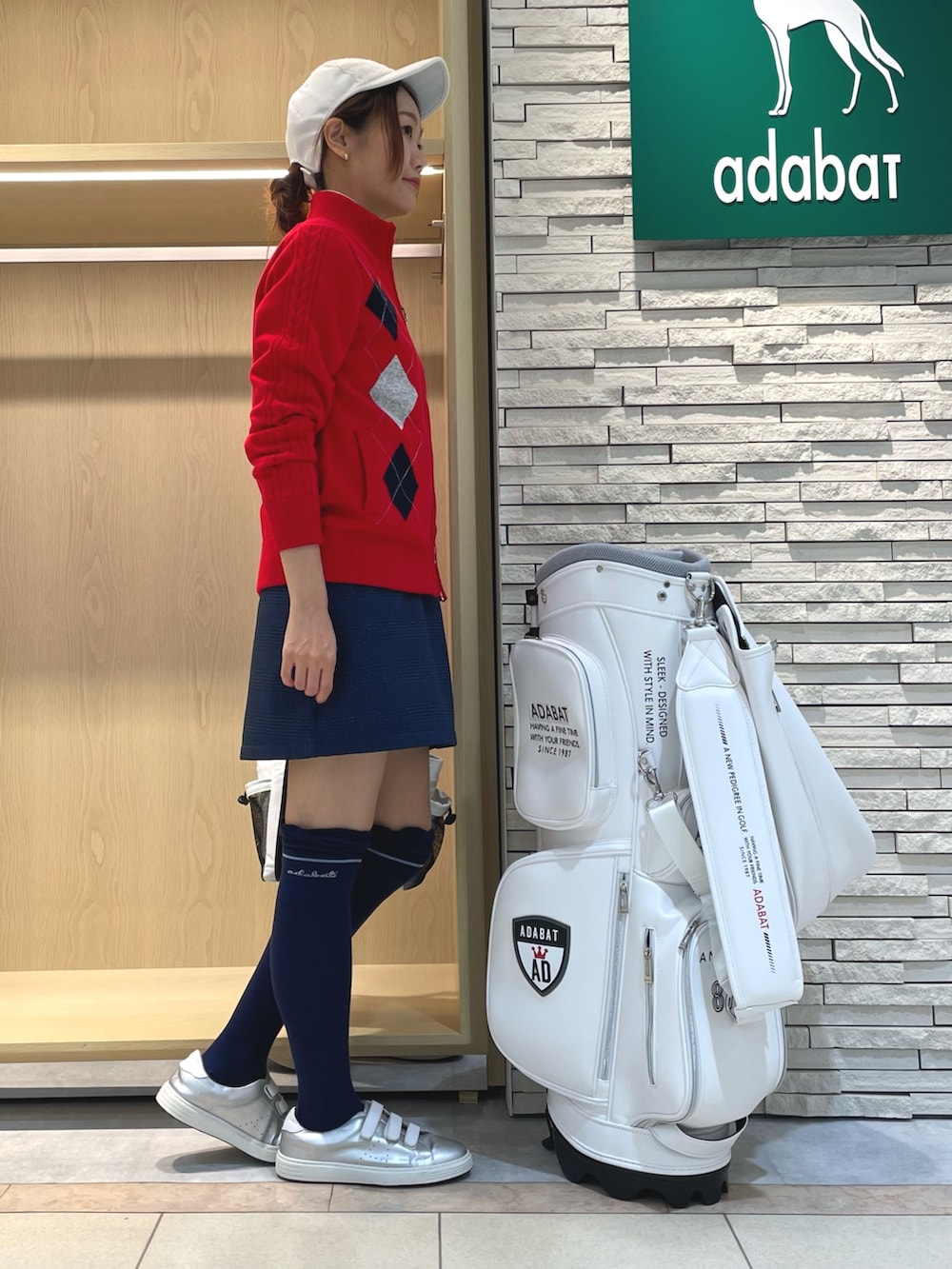 ブルー系のスカート、ホワイト系のトートバッグ、レッド系のニット/セーターを着用したレディースの秋コーディネートの3枚目の写真