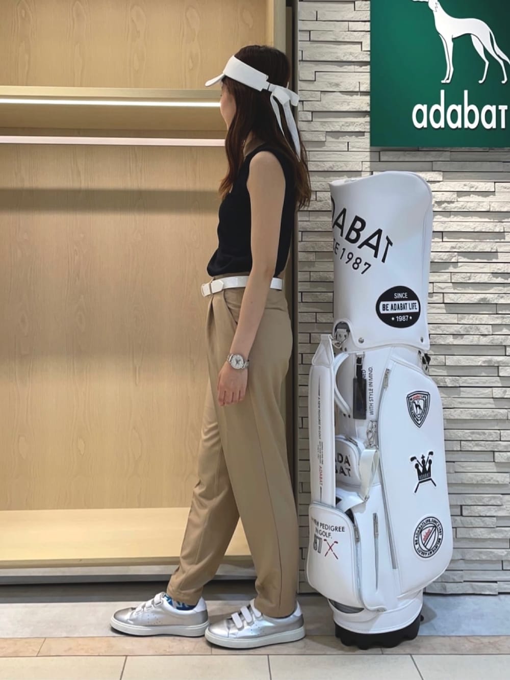 ベージュ系のその他パンツ、ブルー系のポロシャツ、ホワイト系のサンバイザーを着用したレディースの夏コーディネートの2枚目の写真