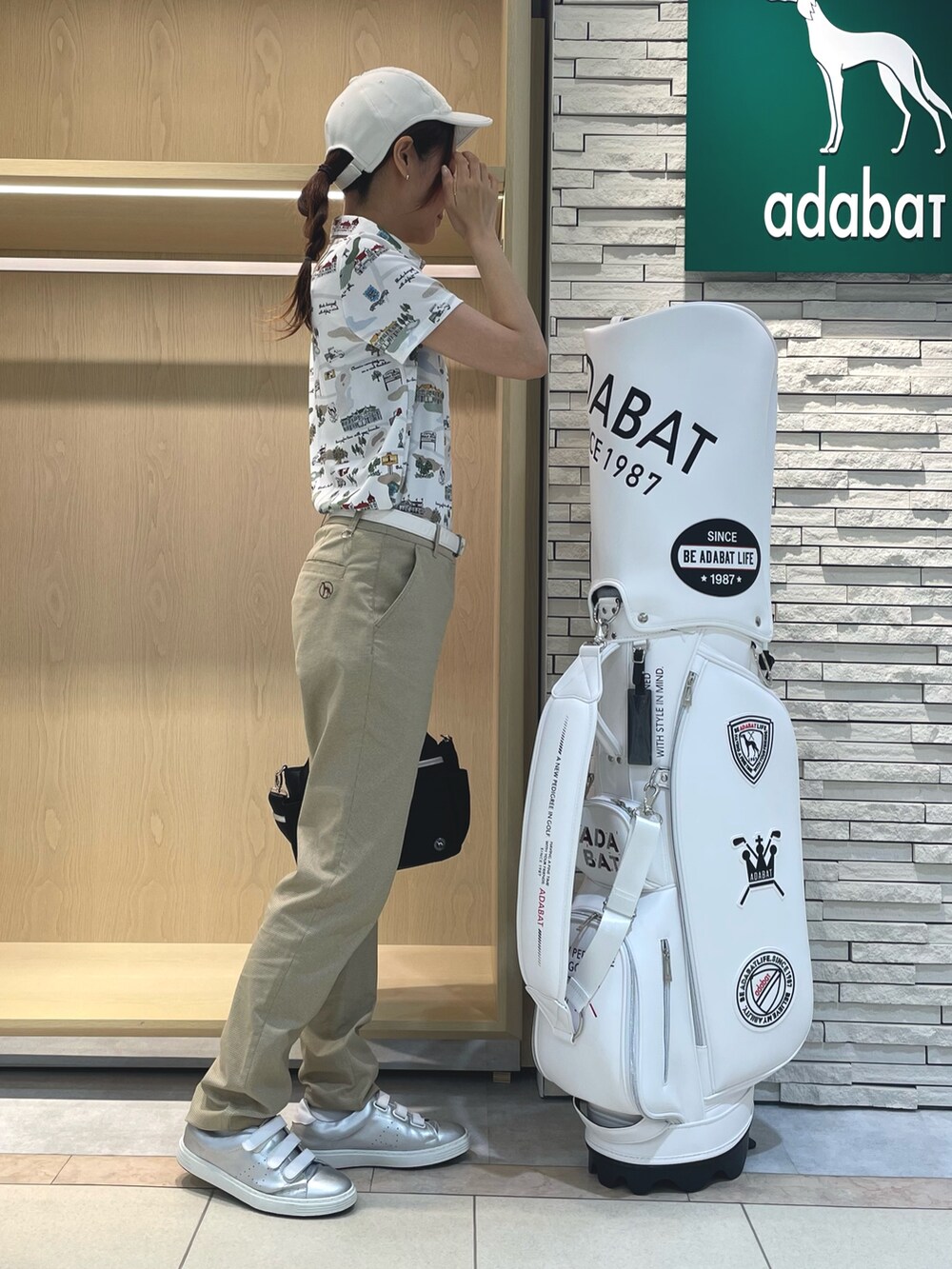 グリーン系のポロシャツ、ベージュ系のその他パンツ、ブラック系のハンドバッグを着用したレディースの秋コーディネートの2枚目の写真