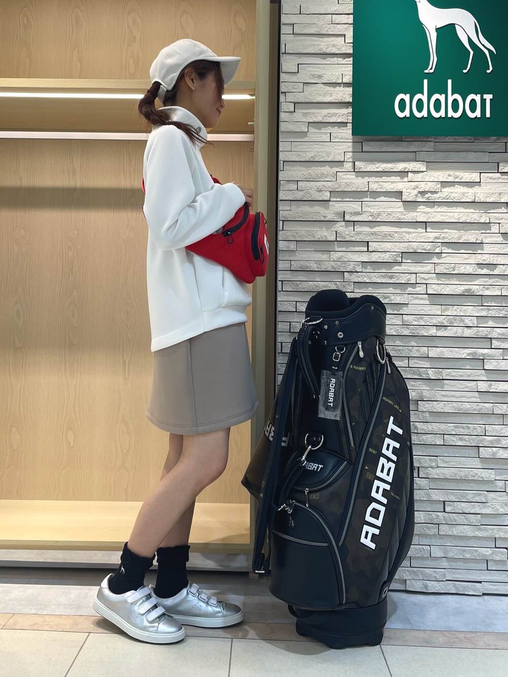 ホワイト系のTシャツ/カットソー、ベージュ系のスカート、レッド系のボディバッグ/ウエストポーチを着用したレディースの秋コーディネートの2枚目の写真