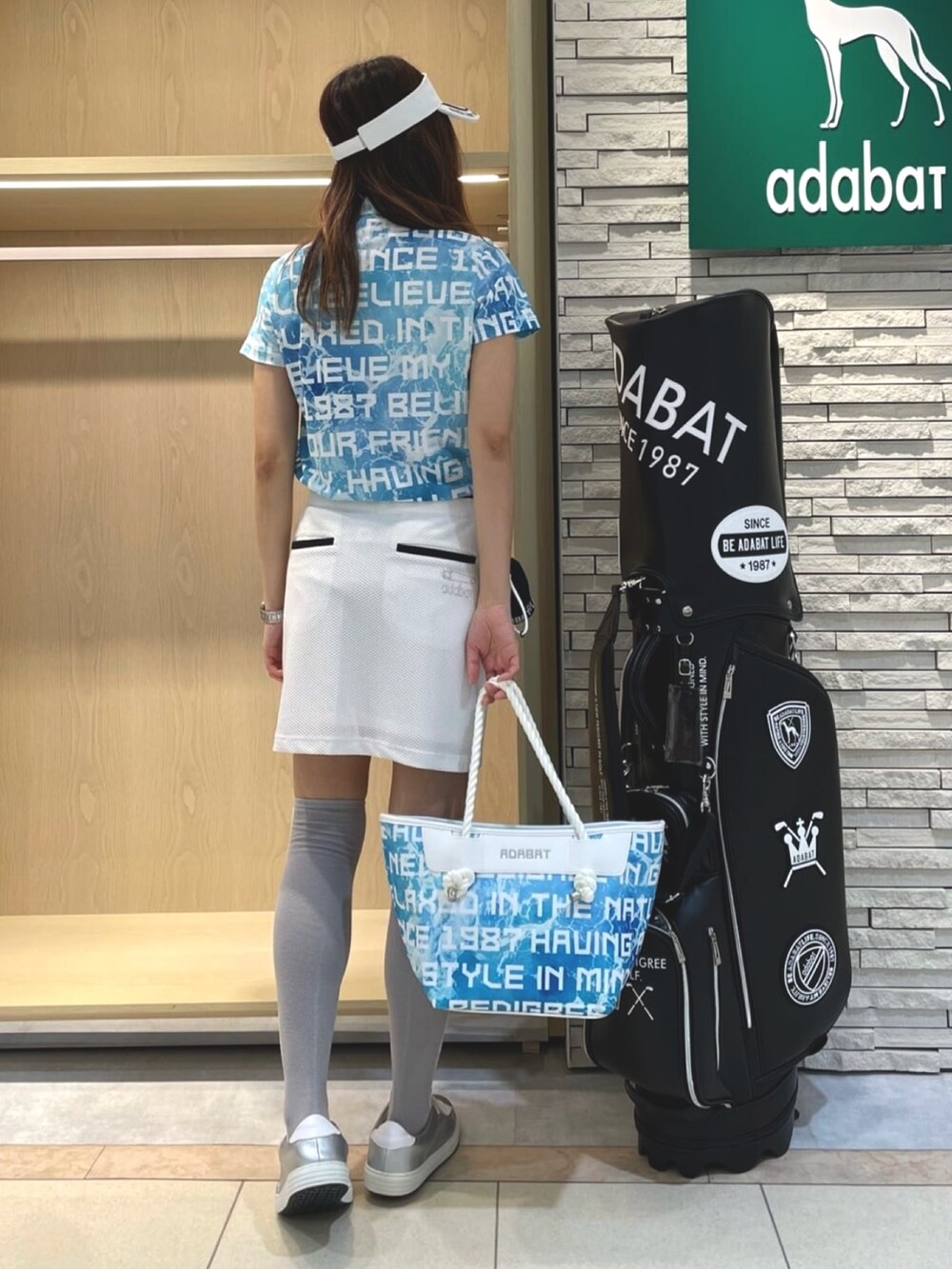 ブルー系のポロシャツ、ホワイト系のスカート、ブルー系のトートバッグを着用したレディースの夏コーディネートの3枚目の写真