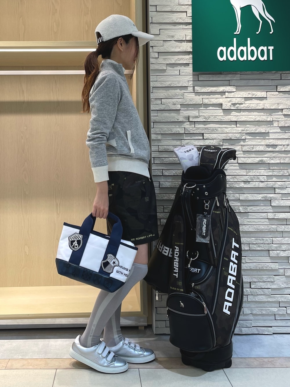 グリーン系のスカート、グレー系のニット/セーター、ホワイト系のTシャツ/カットソーを着用したレディースの冬コーディネートの2枚目の写真