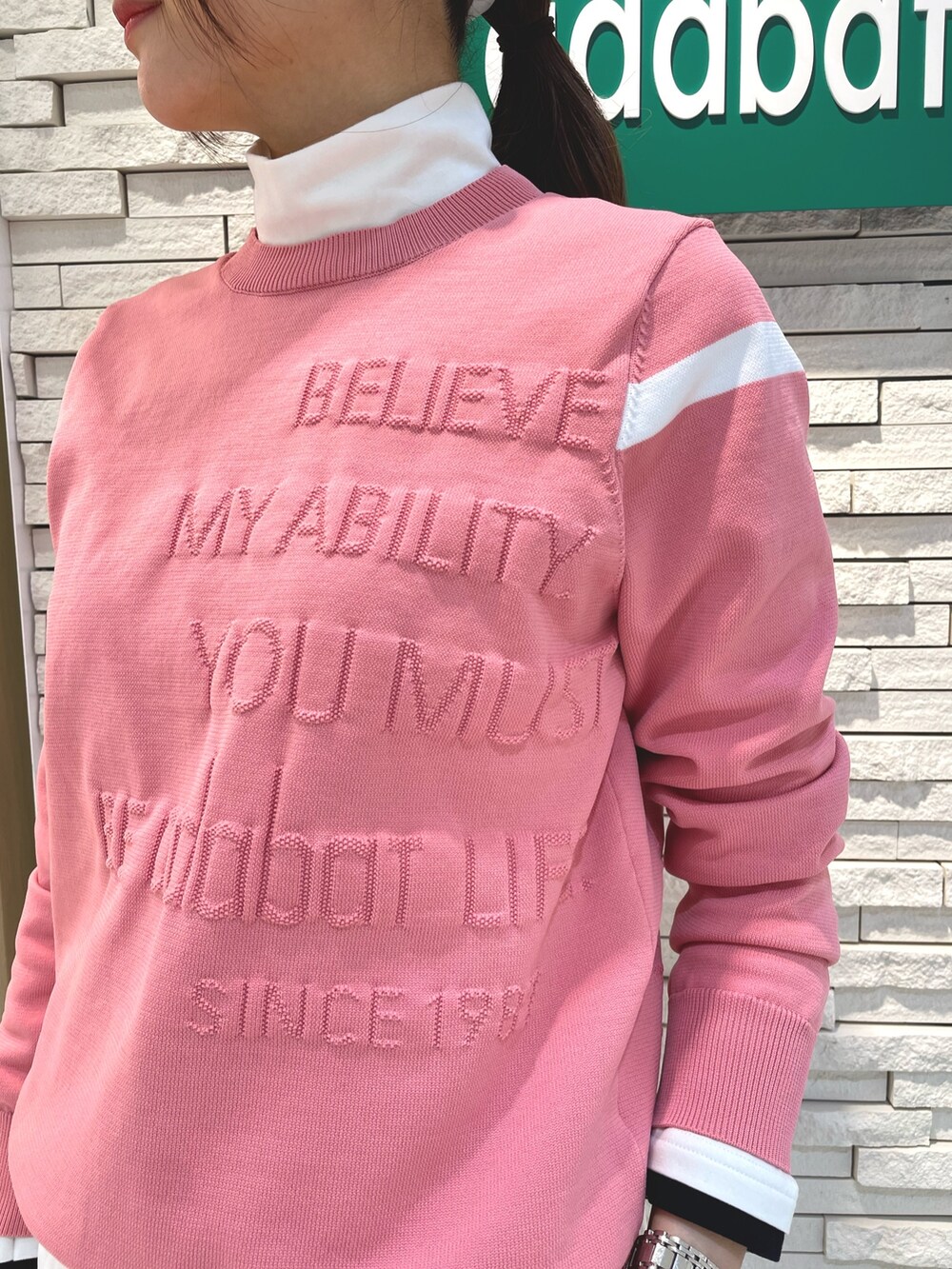 ピンク系のニット/セーター、グリーン系のスカート、ホワイト系のサンバイザーを着用したレディースの冬コーディネートの4枚目の写真