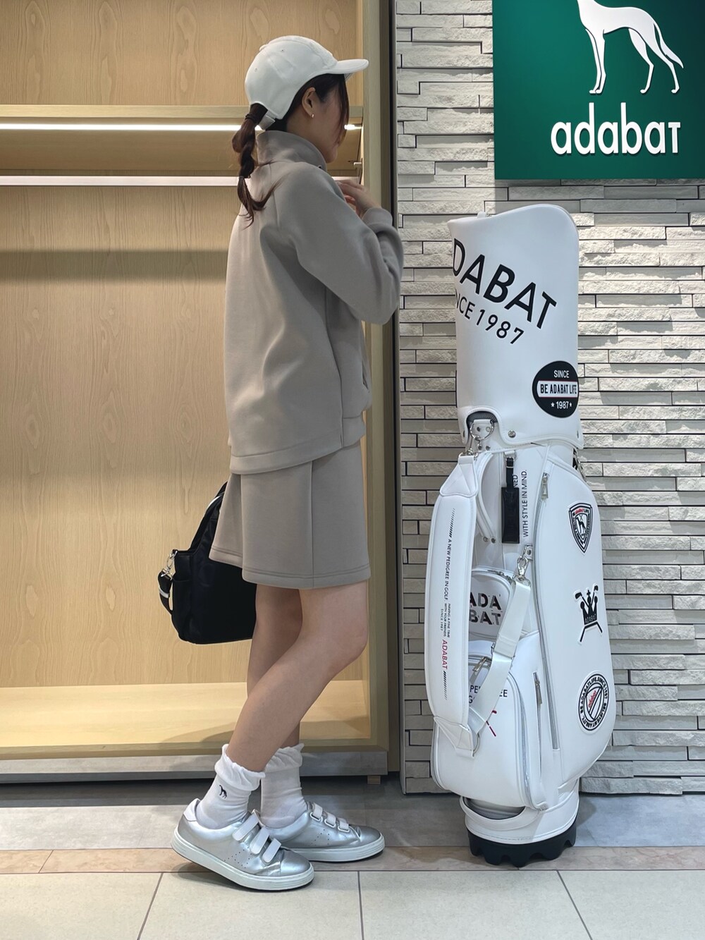 ベージュ系のTシャツ/カットソー、ベージュ系のスカート、ブラック系のハンドバッグを着用したレディースの秋コーディネートの2枚目の写真