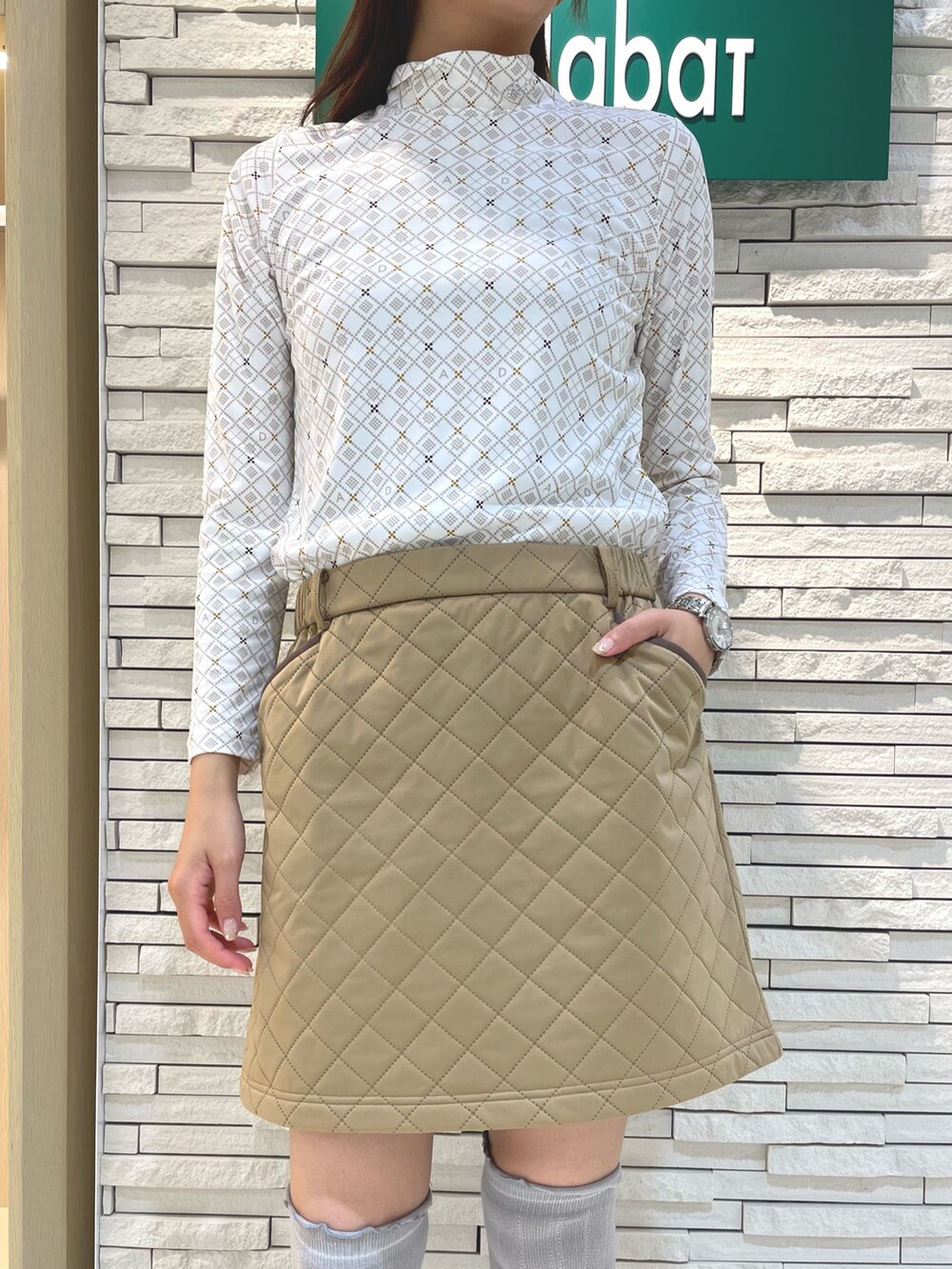 ベージュ系のTシャツ/カットソー、イエロー系のスカート、ブラック系のハンドバッグを着用したレディースの秋コーディネートの3枚目の写真