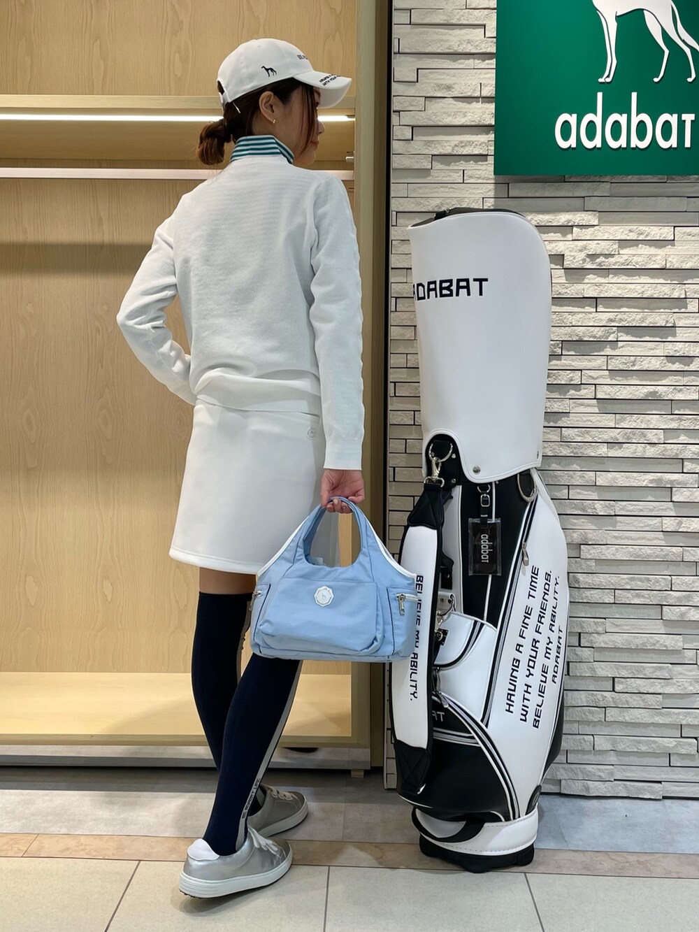 ホワイト系のスカート、ホワイト系のニット/セーター、ブルー系のトートバッグを着用したレディースの春コーディネートの2枚目の写真