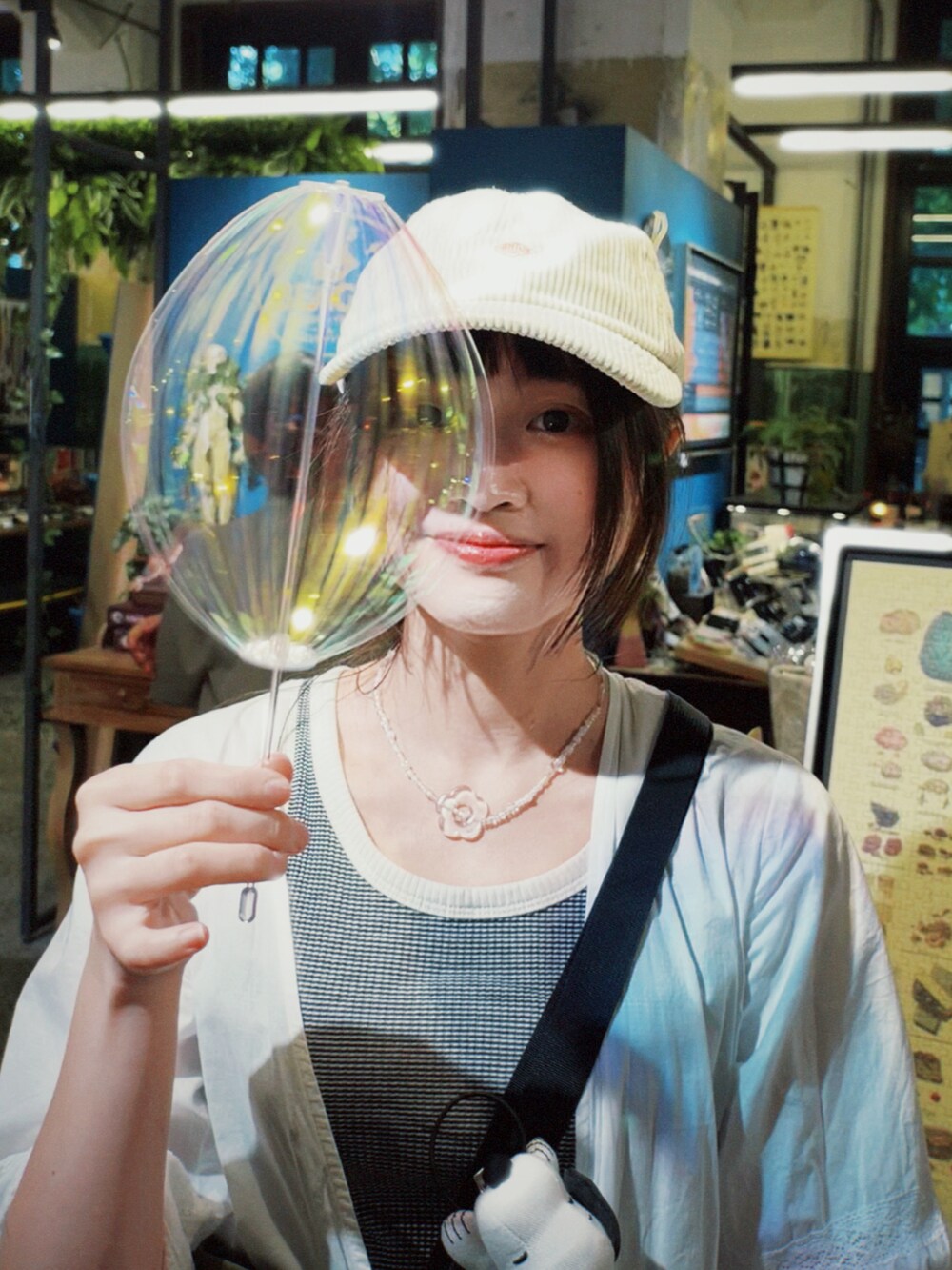 ホワイト系のノーカラージャケット、ブルー系のデニムパンツ、グリーン系のショルダーバッグを着用したレディースの秋コーディネートの3枚目の写真