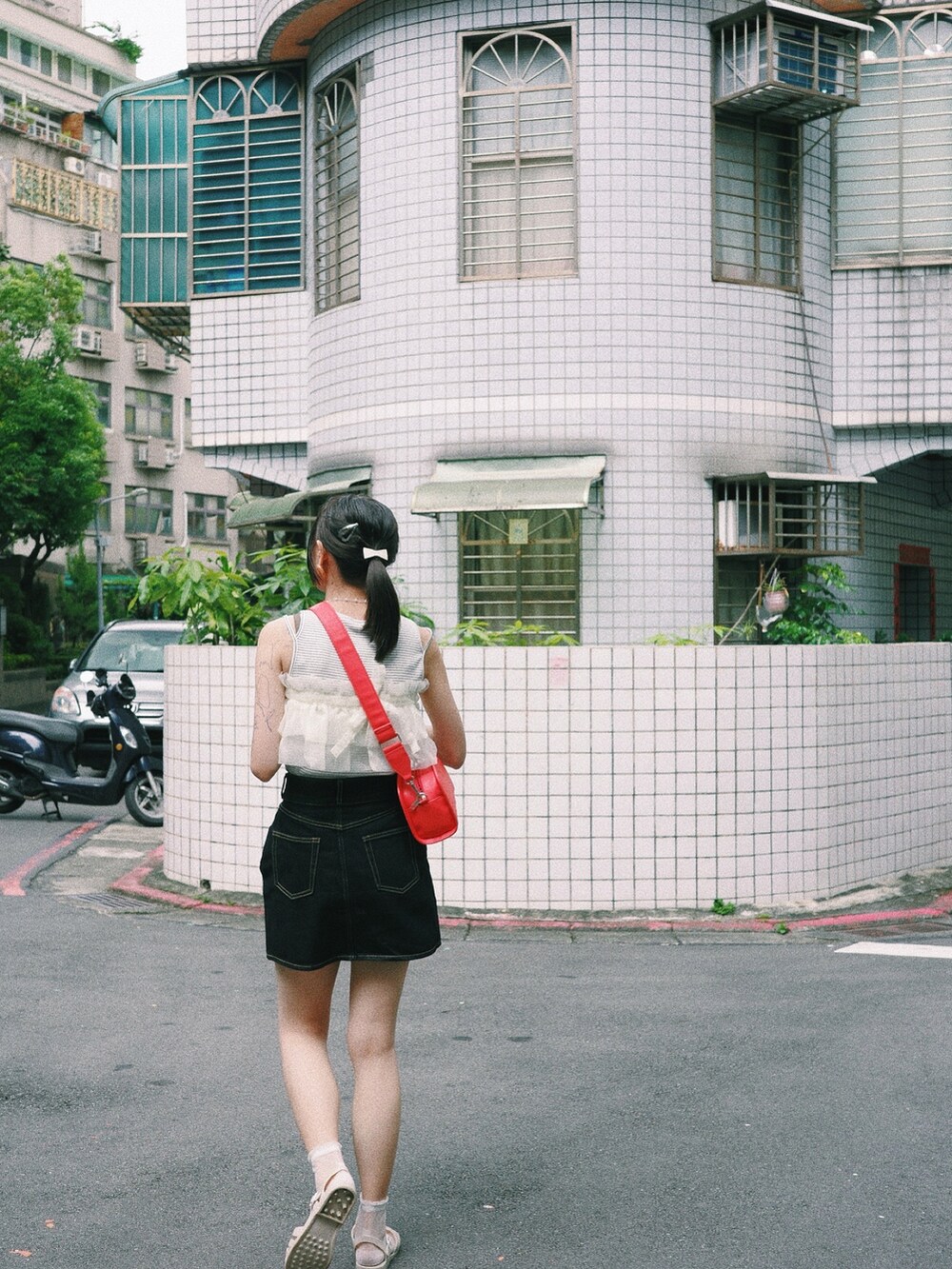 レッド系のショルダーバッグ、ブラック系のデニムスカートを着用したレディースの秋コーディネートの2枚目の写真