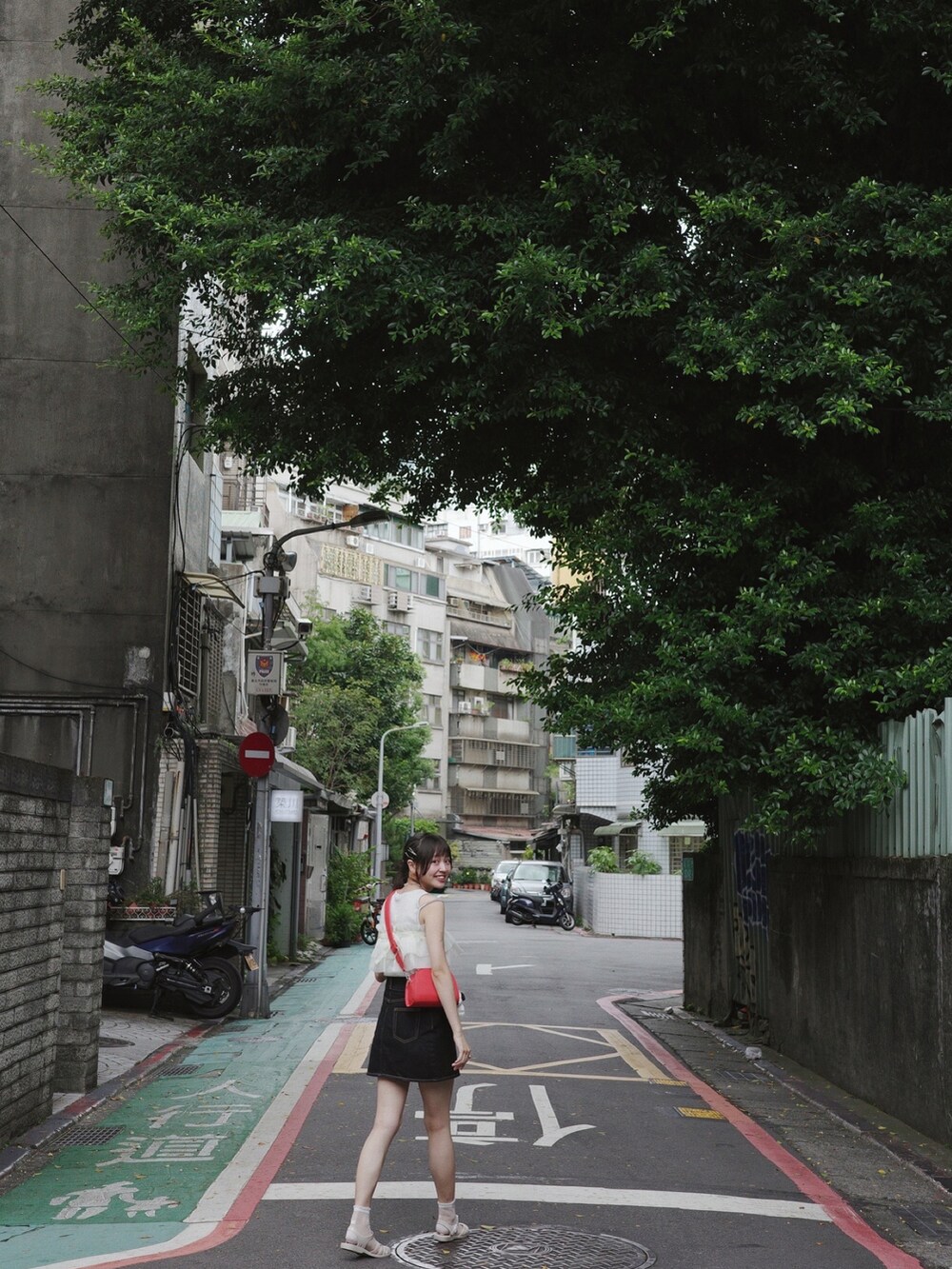 レッド系のショルダーバッグ、ブラック系のデニムスカートを着用したレディースの秋コーディネートの3枚目の写真