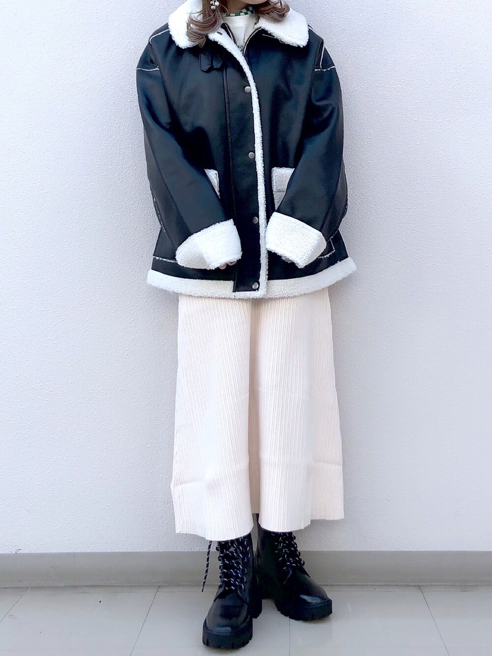 ブラック系のブルゾン、ホワイト系のワンピース、ブラック系のブーツを着用したレディースの冬コーディネートの3枚目の写真