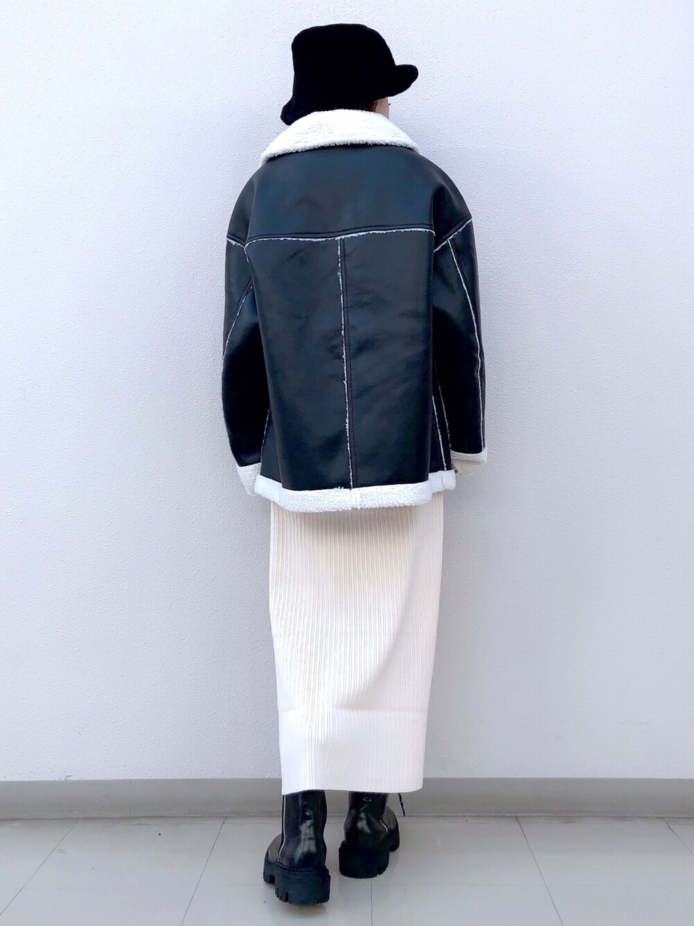 ブラック系のブルゾン、ホワイト系のワンピース、ブラック系のブーツを着用したレディースの冬コーディネートの5枚目の写真