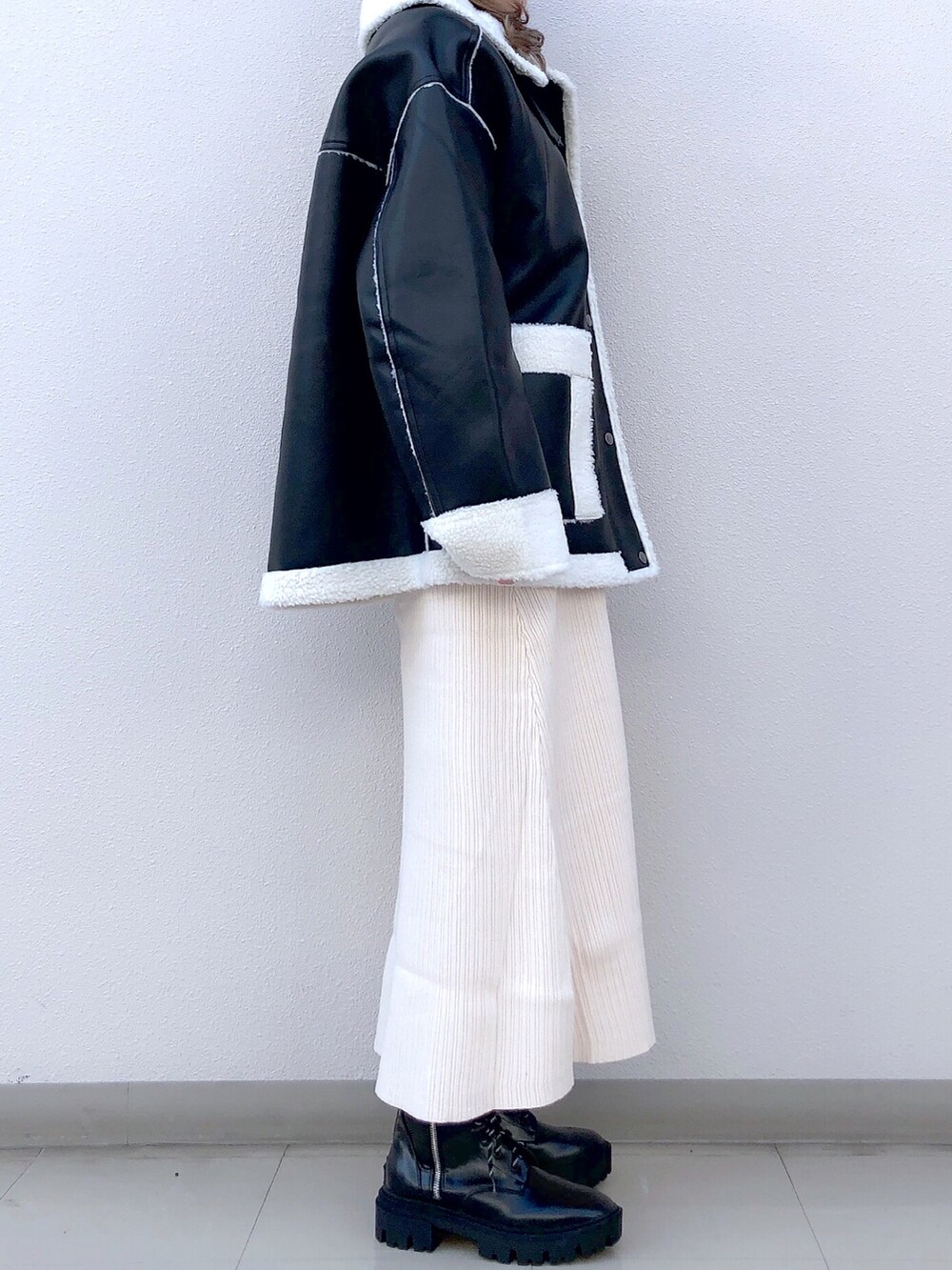 ブラック系のブルゾン、ホワイト系のワンピース、ブラック系のブーツを着用したレディースの冬コーディネートの4枚目の写真