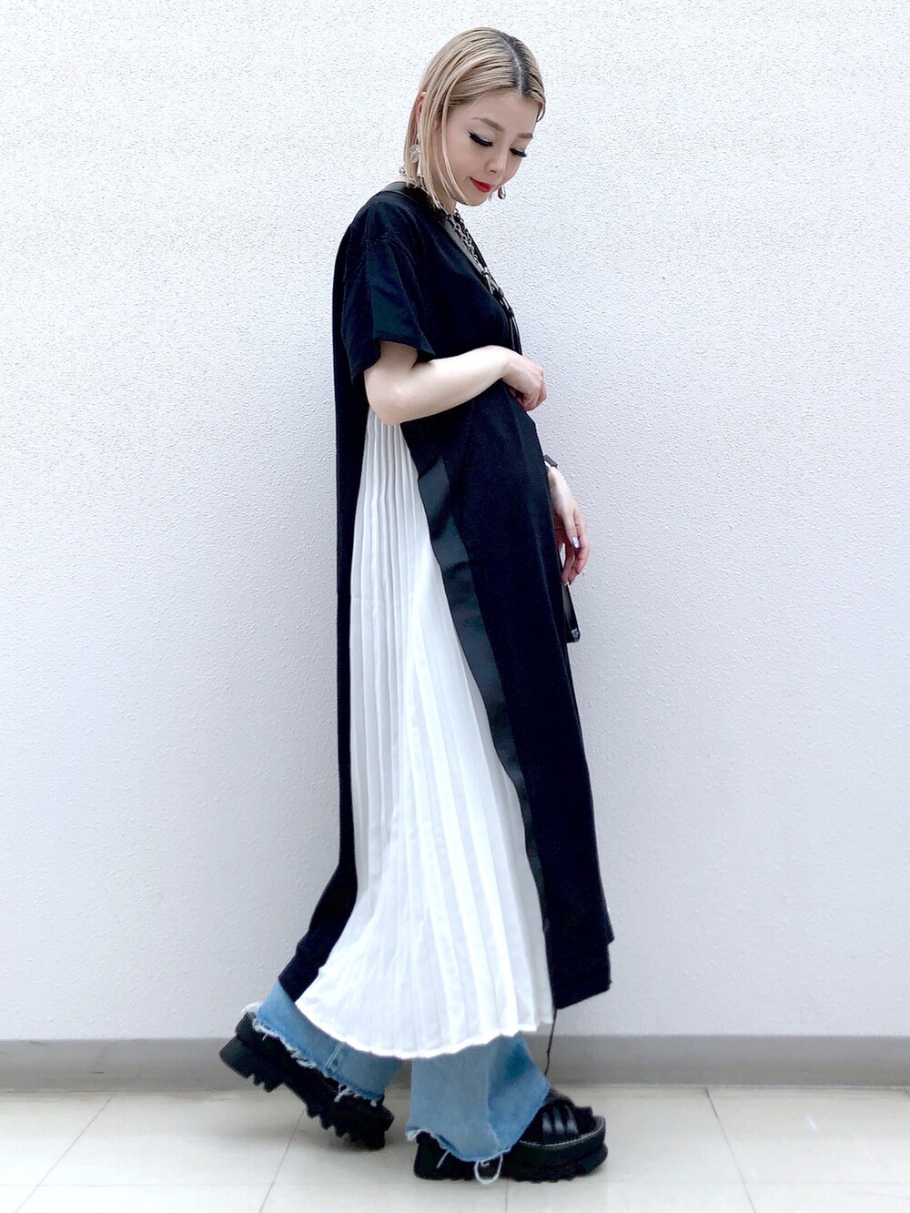 ブラック系のワンピース、ブラック系のショルダーバッグ、ブルー系のデニムパンツを着用したレディースの春コーディネートの2枚目の写真