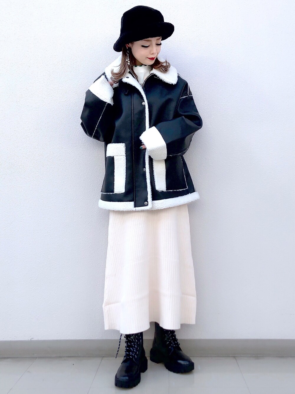 ブラック系のブルゾン、ホワイト系のワンピース、ブラック系のブーツを着用したレディースの冬コーディネートの2枚目の写真