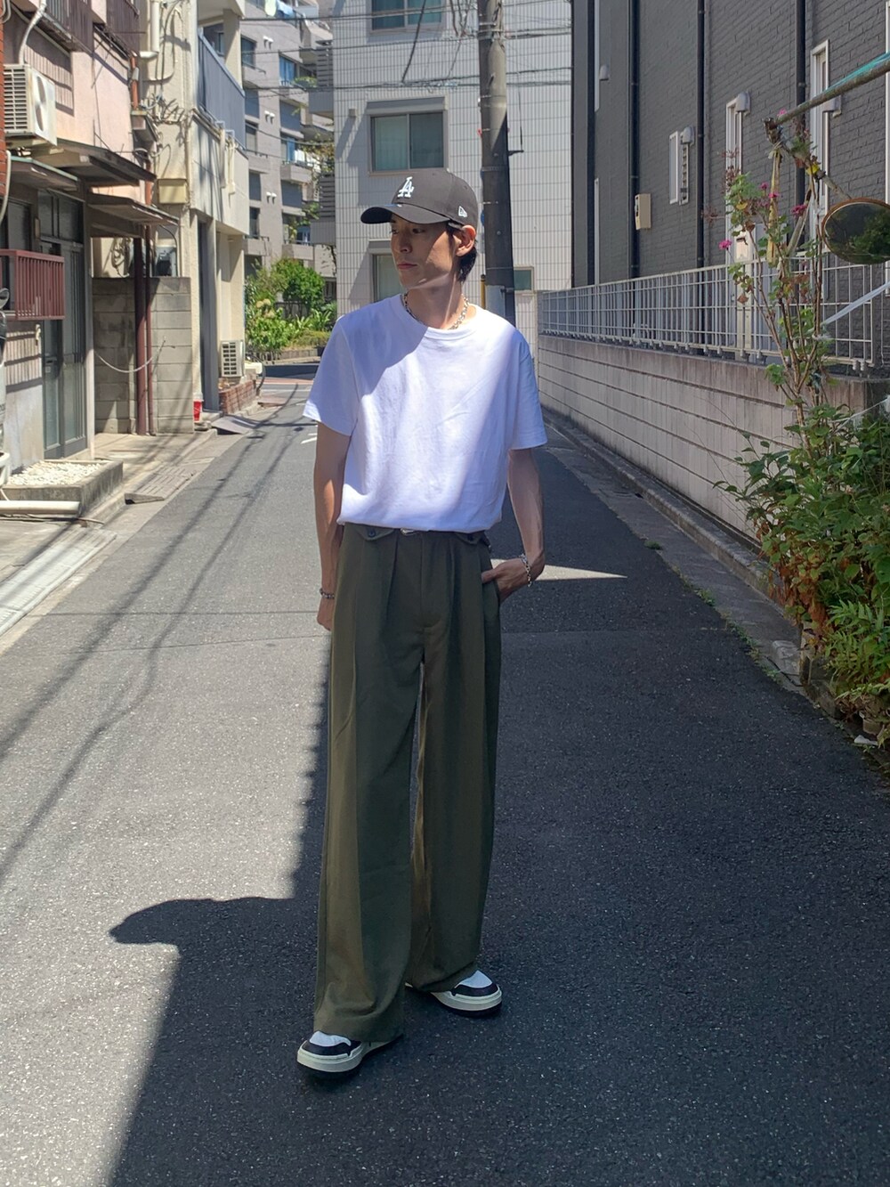 ホワイト系のスニーカー、グリーン系のスラックス、ホワイト系のTシャツ/カットソーを着用したメンズの夏コーディネートの2枚目の写真