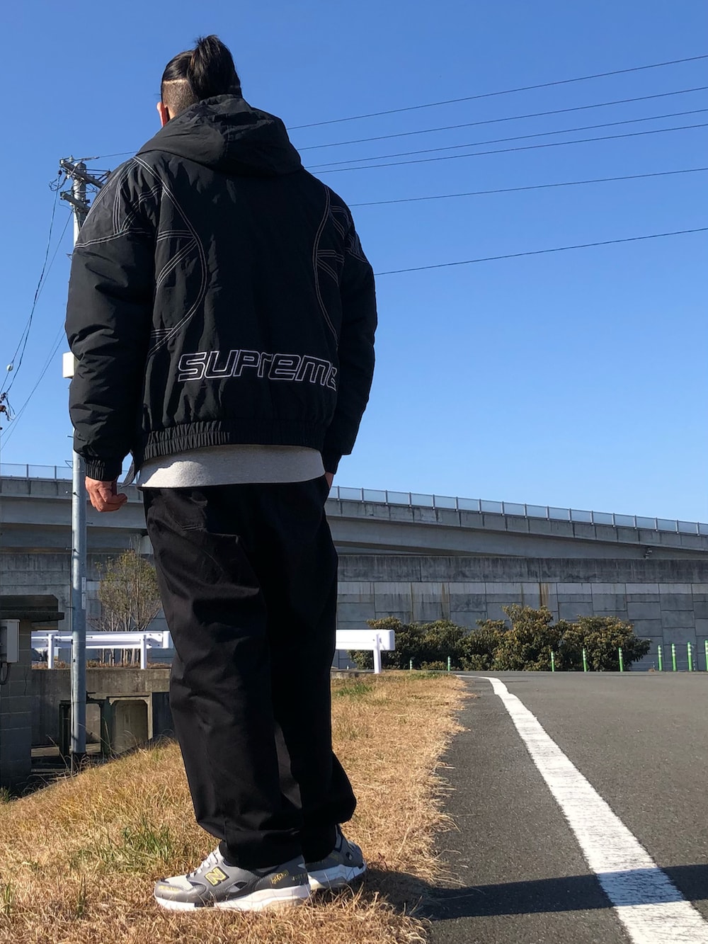 ブラック系のブルゾン、グレー系のスウェット、ブラック系のチノパンツを着用したメンズの冬コーディネートの2枚目の写真