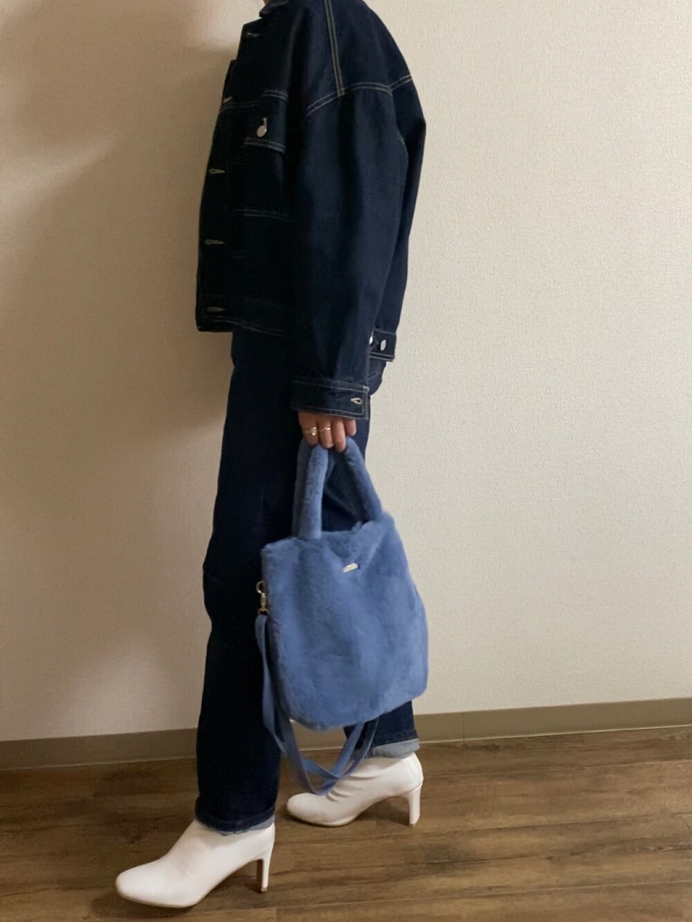 ブルー系のハンドバッグ、ホワイト系のブーツ、ブルー系のデニムパンツを着用したレディースの秋コーディネートの2枚目の写真