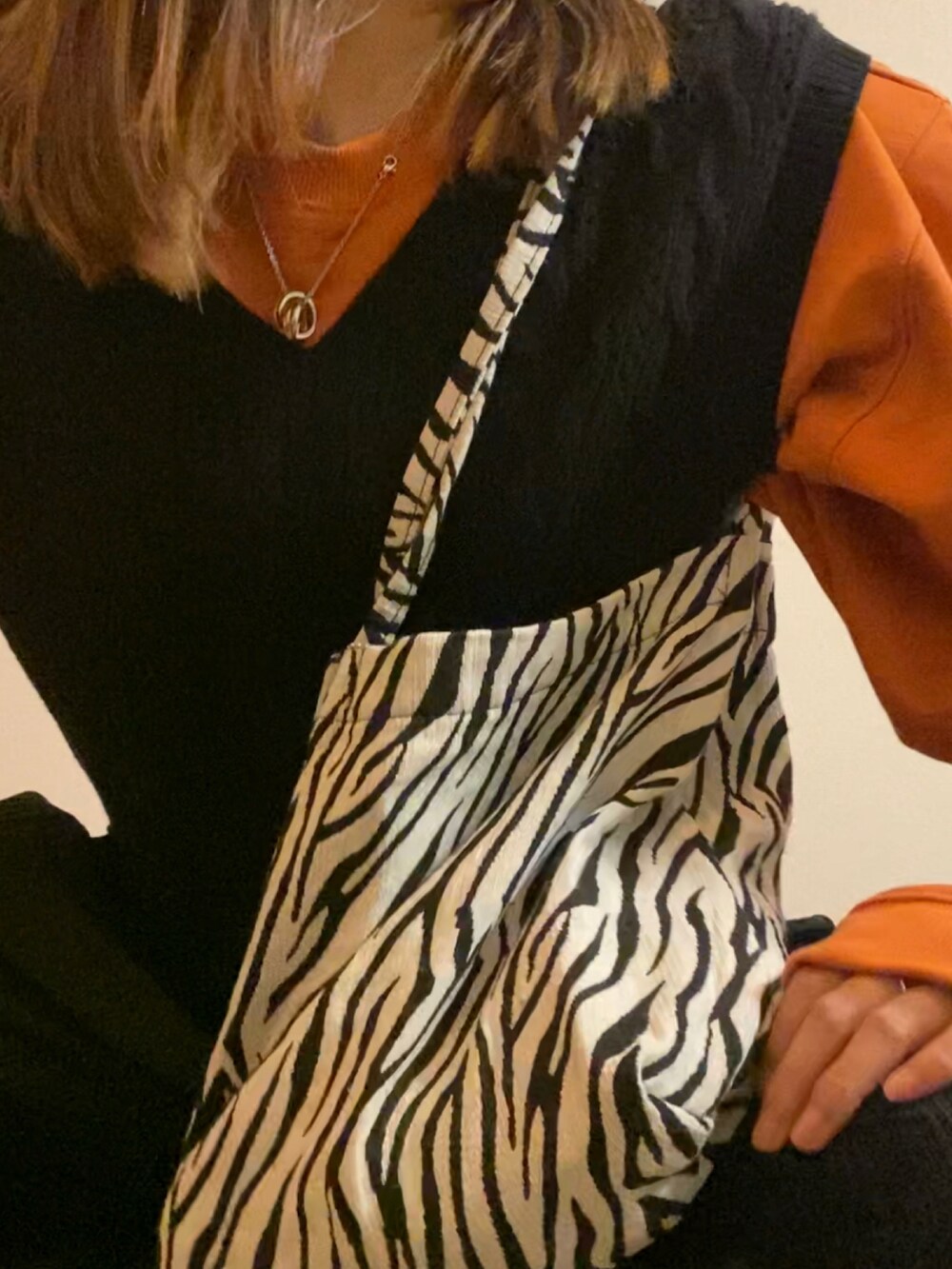 オレンジ系のスウェット、ブラック系のパンツ、ブラウン系のローファーを着用したレディースの秋コーディネートの2枚目の写真