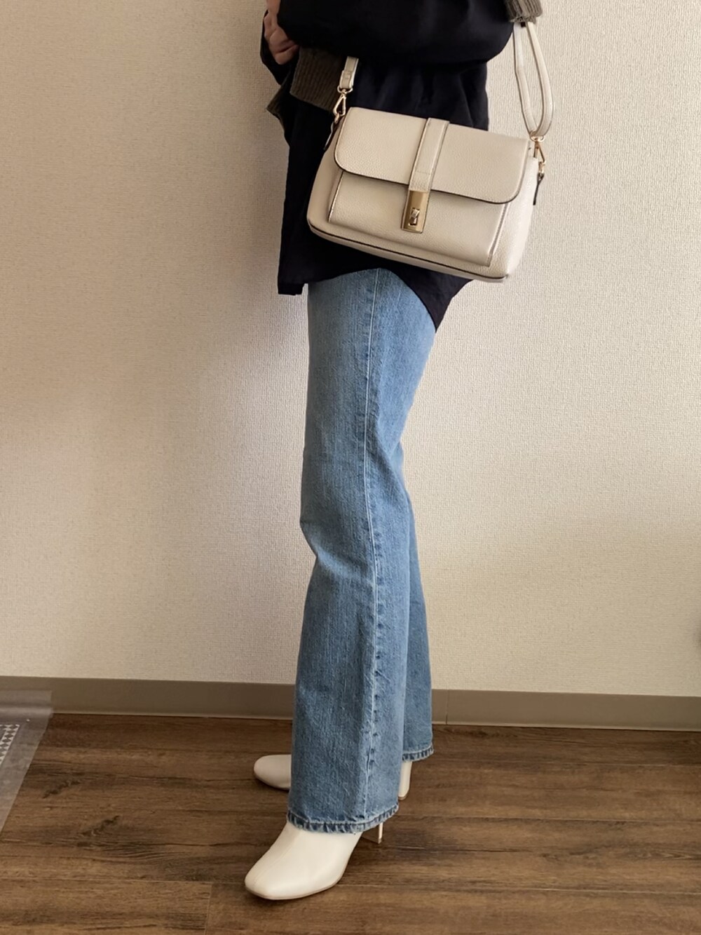 ブルー系のデニムパンツ、ホワイト系のブーツ、グリーン系のニット/セーターを着用したレディースの冬コーディネートの2枚目の写真