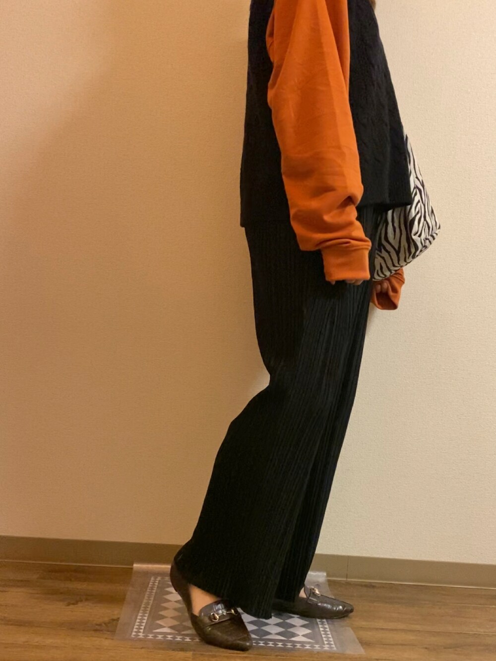 オレンジ系のスウェット、ブラック系のパンツ、ブラウン系のローファーを着用したレディースの秋コーディネートの3枚目の写真