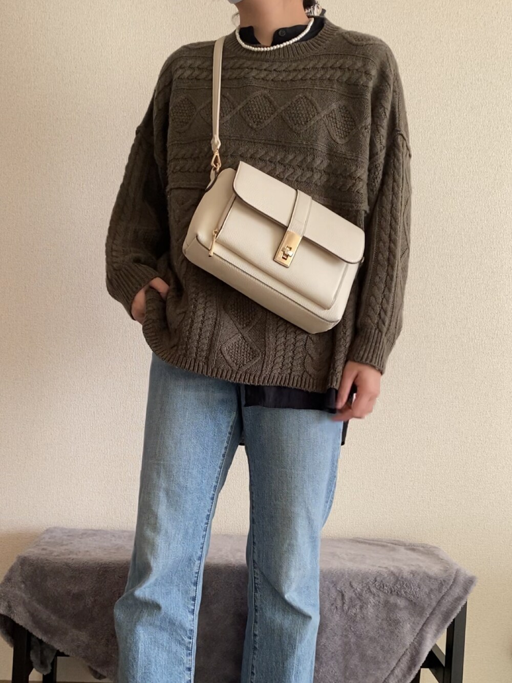 ブルー系のデニムパンツ、ホワイト系のブーツ、グリーン系のニット/セーターを着用したレディースの冬コーディネートの3枚目の写真