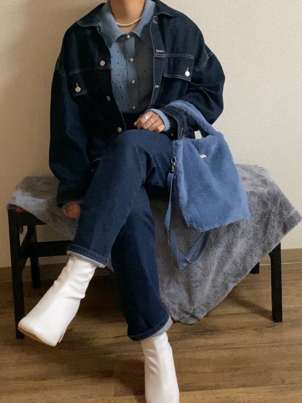 ブルー系のハンドバッグ、ホワイト系のブーツ、ブルー系のデニムパンツを着用したレディースの秋コーディネートの3枚目の写真