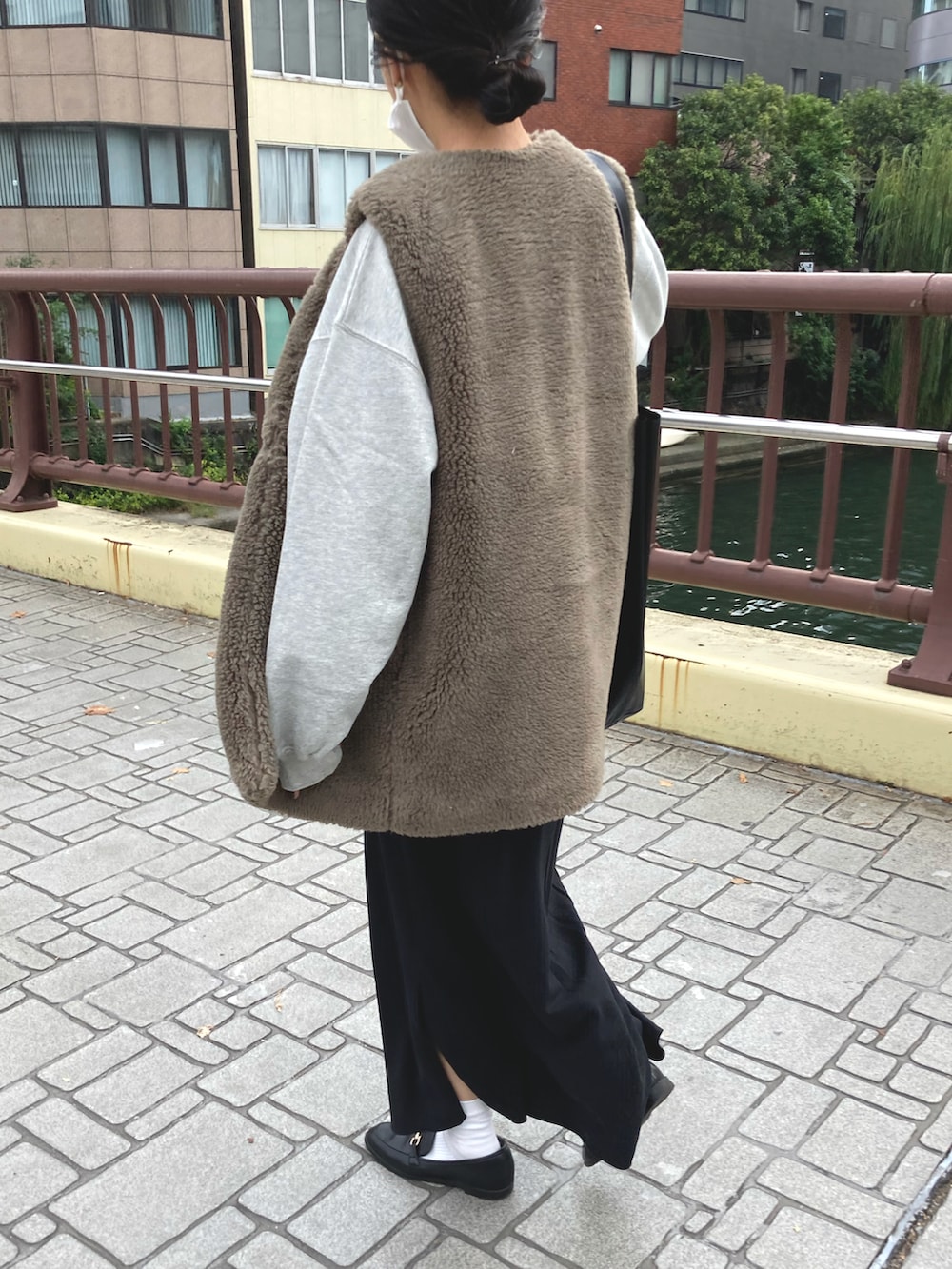 ブラック系のスカート、ベージュ系のベスト、グレー系のスウェットを着用したレディースの秋コーディネートの3枚目の写真