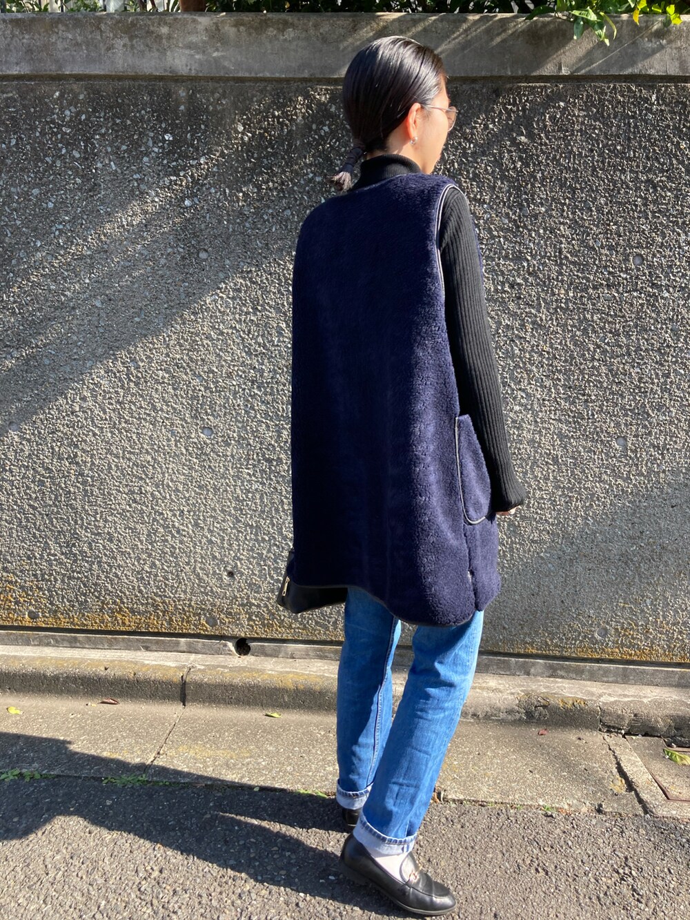 ブルー系のベスト、ブルー系のデニムパンツ、ブラック系のニット/セーターを着用したレディースの秋コーディネートの2枚目の写真