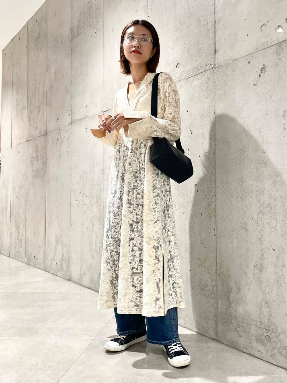 ブルー系のデニムパンツ、ブラック系のショルダーバッグ、ホワイト系のワンピースを着用したレディースの秋コーディネートの2枚目の写真