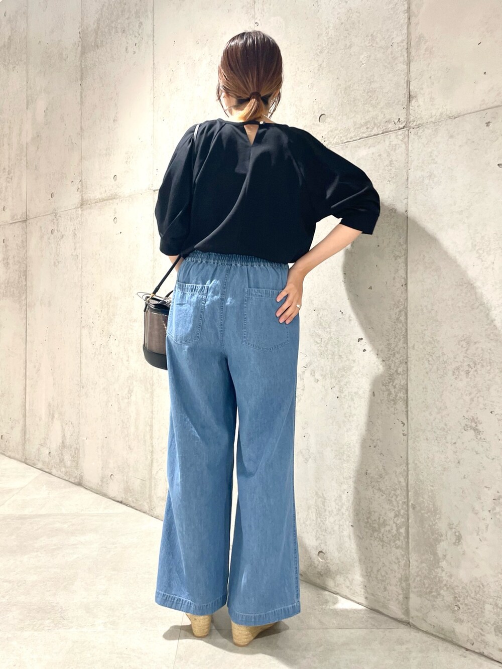 ベージュ系のかごバッグ、ブラウン系のサンダル、ブルー系のデニムパンツを着用したレディースの夏コーディネートの2枚目の写真