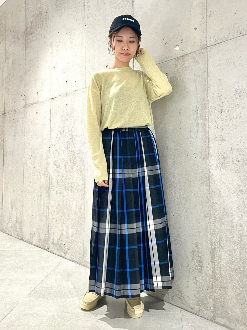 ブラック系のスカート、イエロー系のTシャツ/カットソー、ブラック系のキャップを着用したレディースの秋コーディネートの2枚目の写真