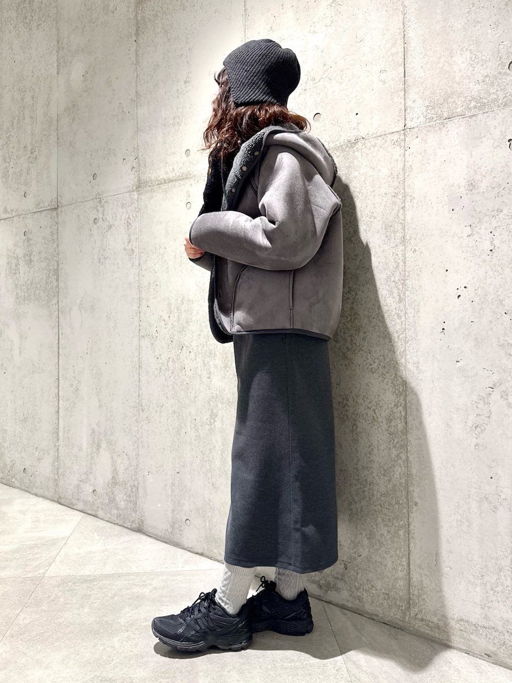 ブラック系のムートンコート、グレー系のニット/セーター、グレー系のスカートを着用したレディースの冬コーディネートの3枚目の写真