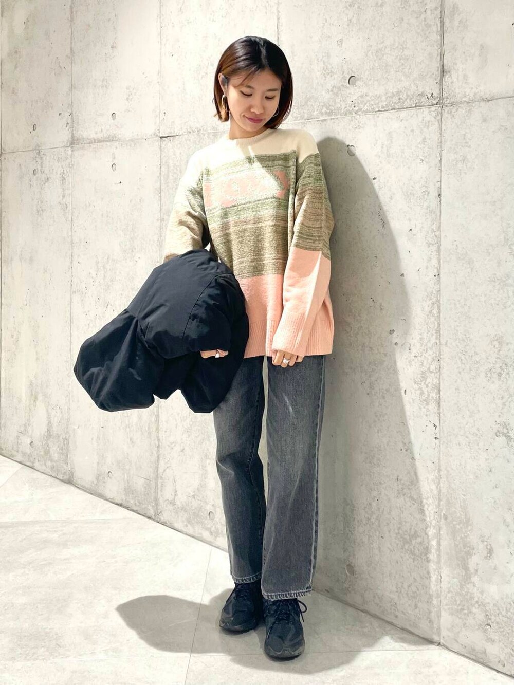 ブラック系のデニムパンツ、ブラック系のダウンジャケット/コート、ピンク系のニット/セーターを着用したレディースの秋コーディネートの4枚目の写真