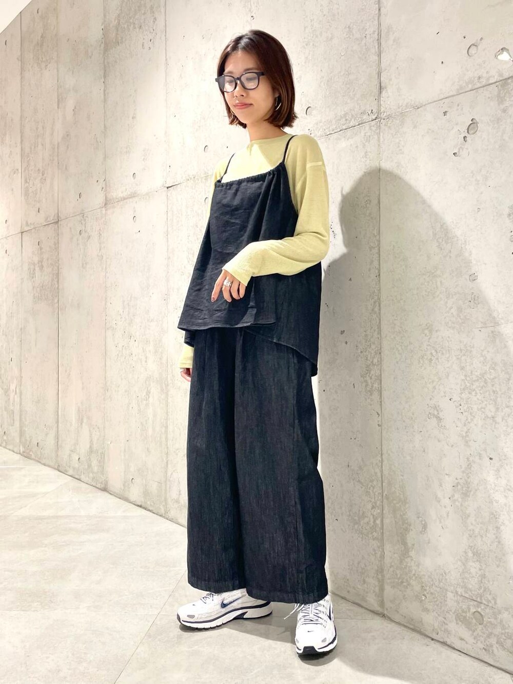 ブラック系のサロペット/オーバーオール、イエロー系のTシャツ/カットソー、ホワイト系のスニーカーを着用したレディースの秋コーディネートの2枚目の写真