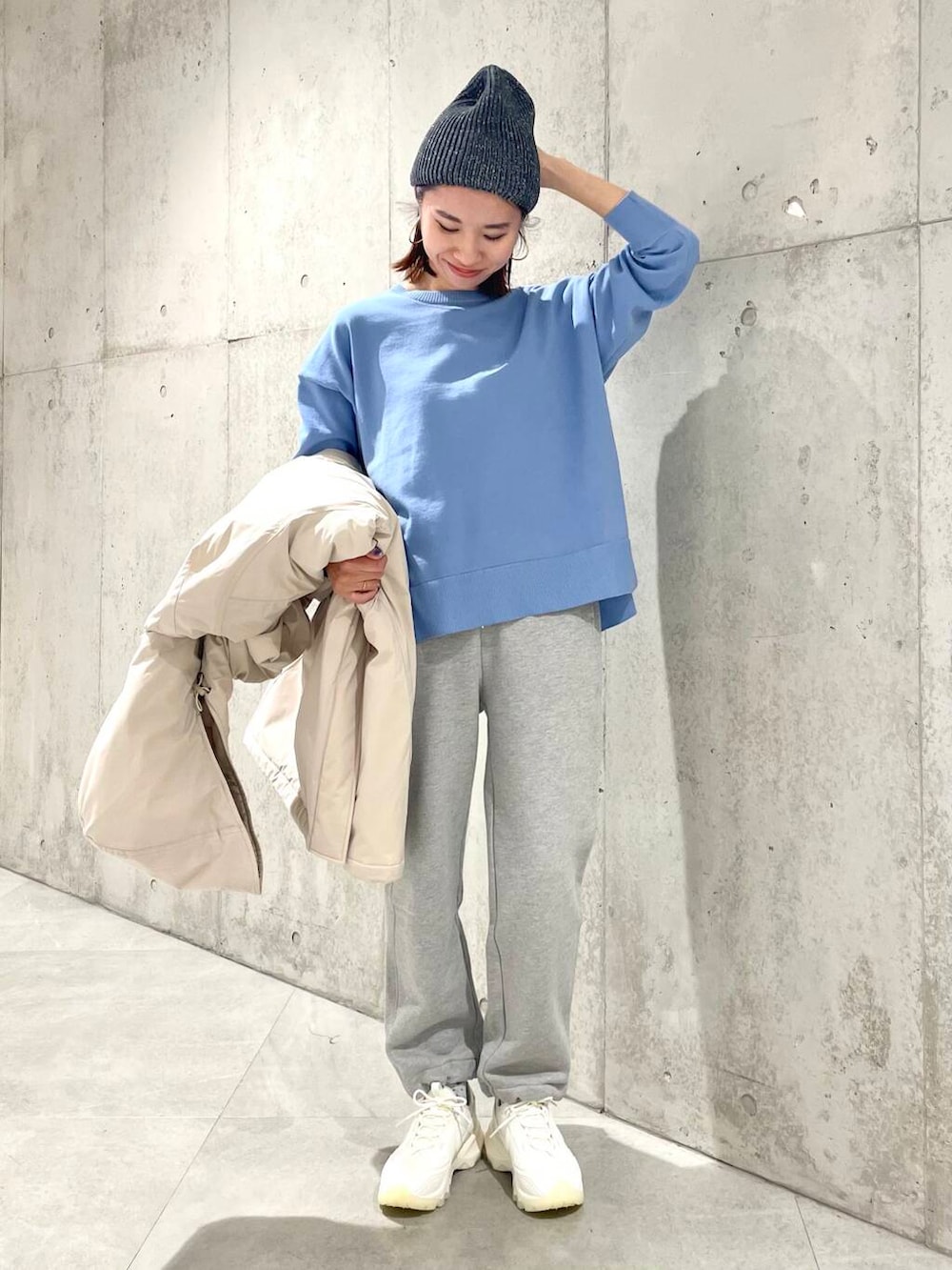 ホワイト系のスニーカー、ベージュ系のダウンジャケット/コート、ブルー系のニット/セーターを着用したレディースの冬コーディネートの6枚目の写真