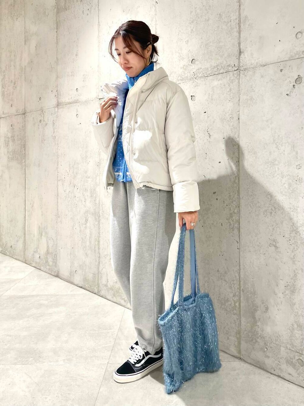 ブラック系のスニーカー、ブルー系のニット/セーター、ブルー系のトートバッグを着用したレディースの冬コーディネートの3枚目の写真