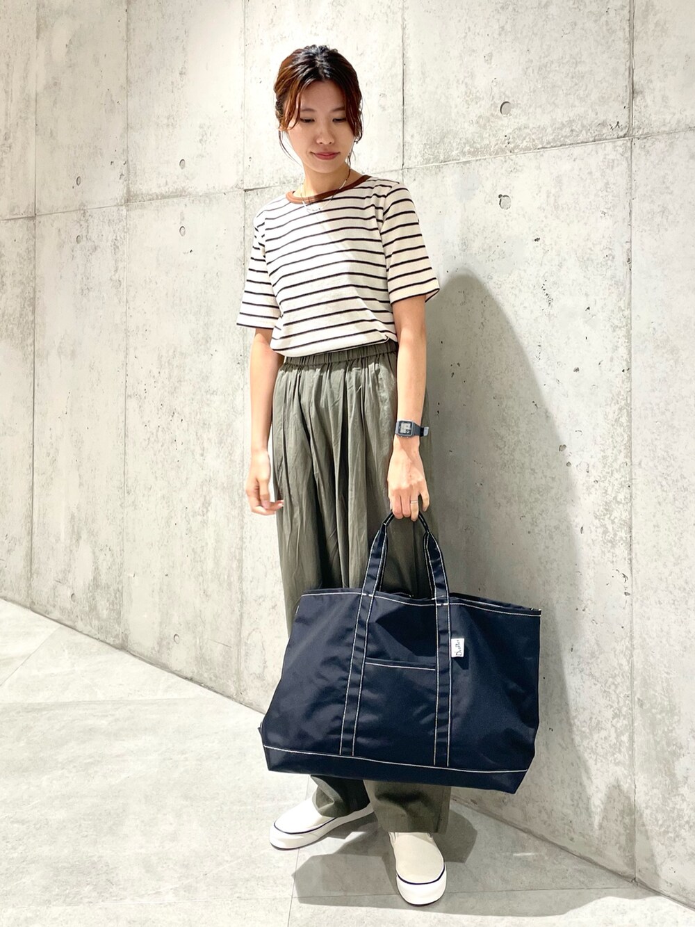 ホワイト系のスリッポン、ブラック系のトートバッグ、グリーン系のその他パンツを着用したレディースの夏コーディネートの3枚目の写真