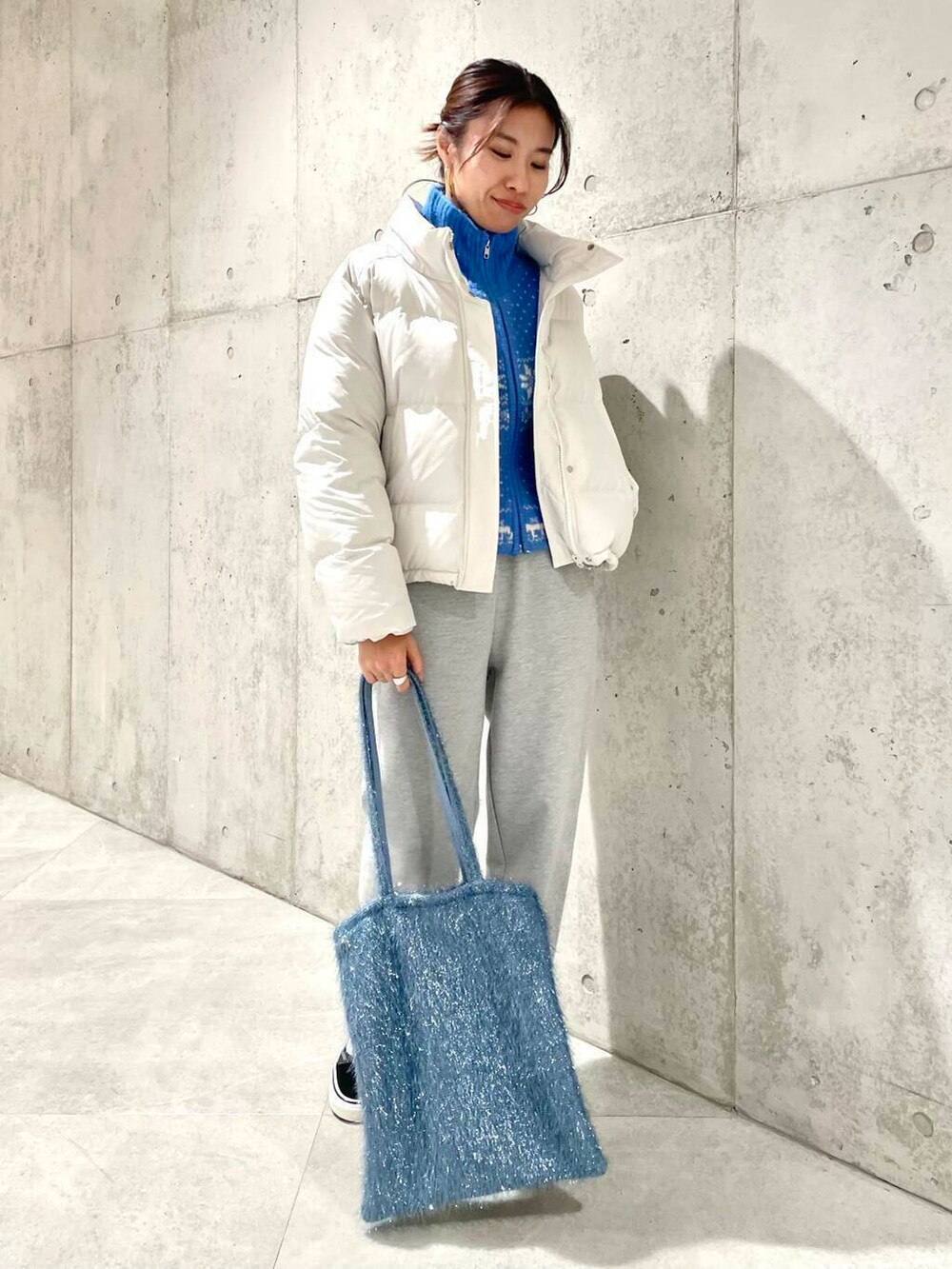 ブラック系のスニーカー、ブルー系のニット/セーター、ブルー系のトートバッグを着用したレディースの冬コーディネートの2枚目の写真