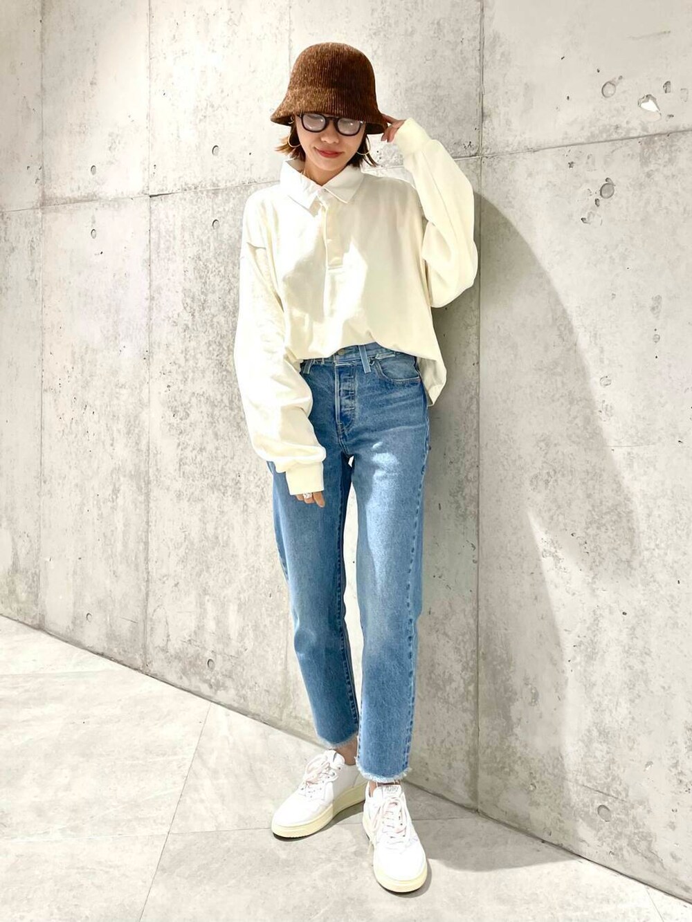 ベージュ系のポロシャツ、ブルー系のデニムパンツ、ホワイト系のスニーカーを着用したレディースの夏コーディネートの2枚目の写真