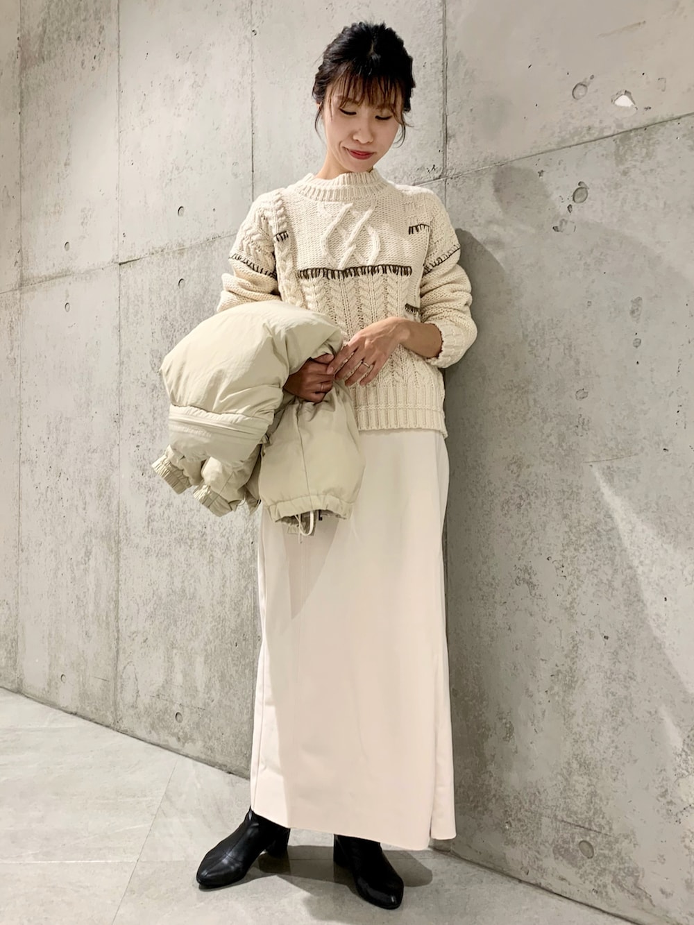 ホワイト系のダウンジャケット/コート、ホワイト系のニット/セーター、ホワイト系のスカートを着用したレディースの冬コーディネートの2枚目の写真