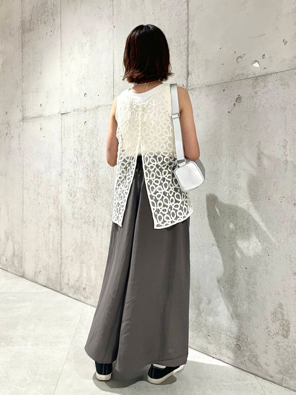 ホワイト系のタンクトップ、ホワイト系のベスト、シルバー系のショルダーバッグを着用したレディースの夏コーディネートの4枚目の写真