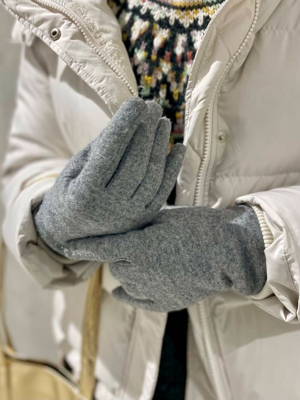 ホワイト系のダウンジャケット/コート、ベージュ系のスカート、グレー系のニット/セーターを着用したレディースの冬コーディネートの5枚目の写真