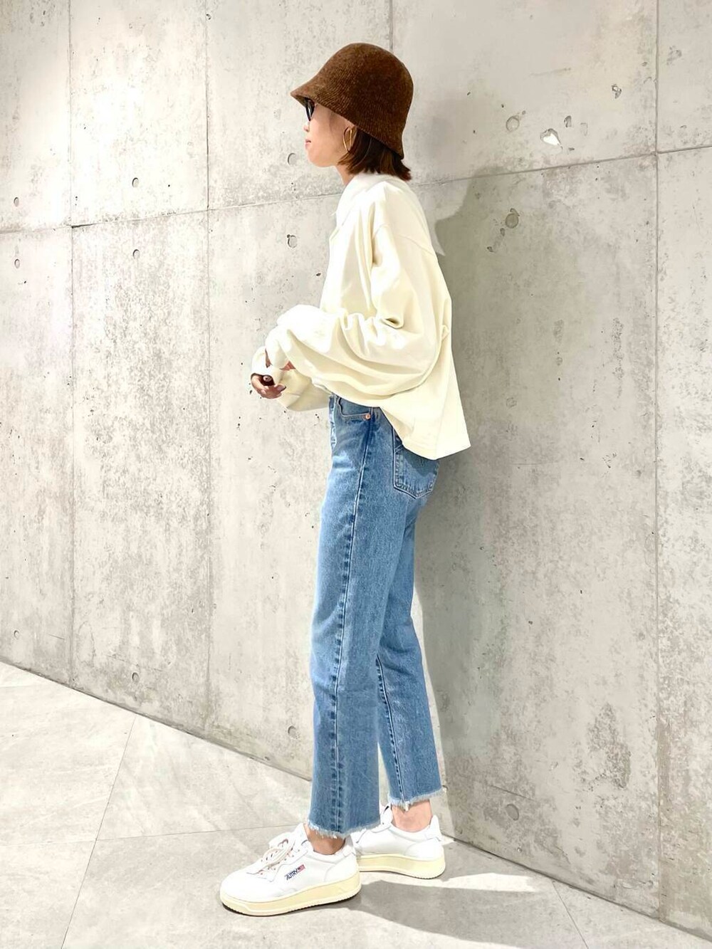 ベージュ系のポロシャツ、ブルー系のデニムパンツ、ホワイト系のスニーカーを着用したレディースの夏コーディネートの5枚目の写真