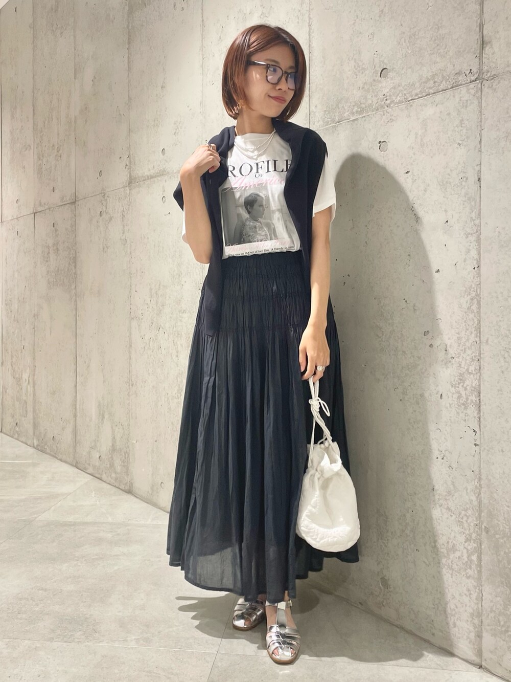 ホワイト系のショルダーバッグ、ブラック系のカーディガン/ボレロ、ブラック系のスカートを着用したレディースの夏コーディネートの2枚目の写真