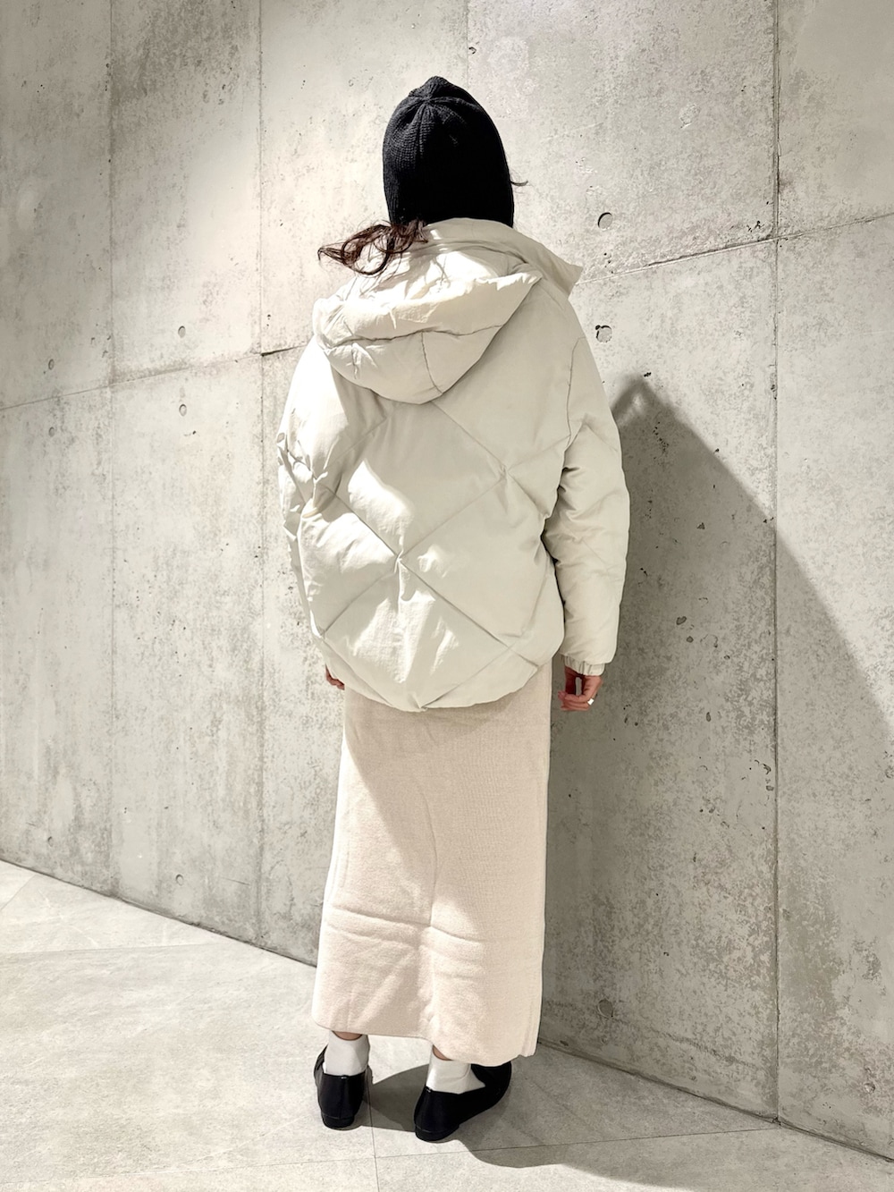 ホワイト系のスカート、グリーン系のニット/セーター、ホワイト系のダウンジャケット/コートを着用したレディースの秋コーディネートの4枚目の写真