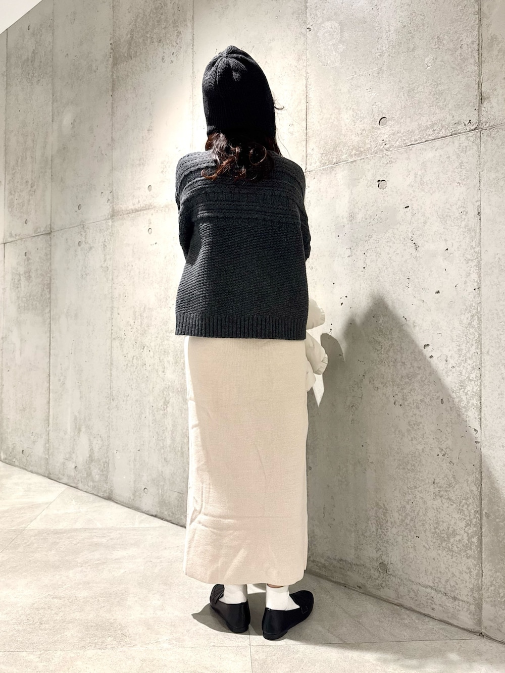 ホワイト系のスカート、グリーン系のニット/セーター、ホワイト系のダウンジャケット/コートを着用したレディースの秋コーディネートの7枚目の写真