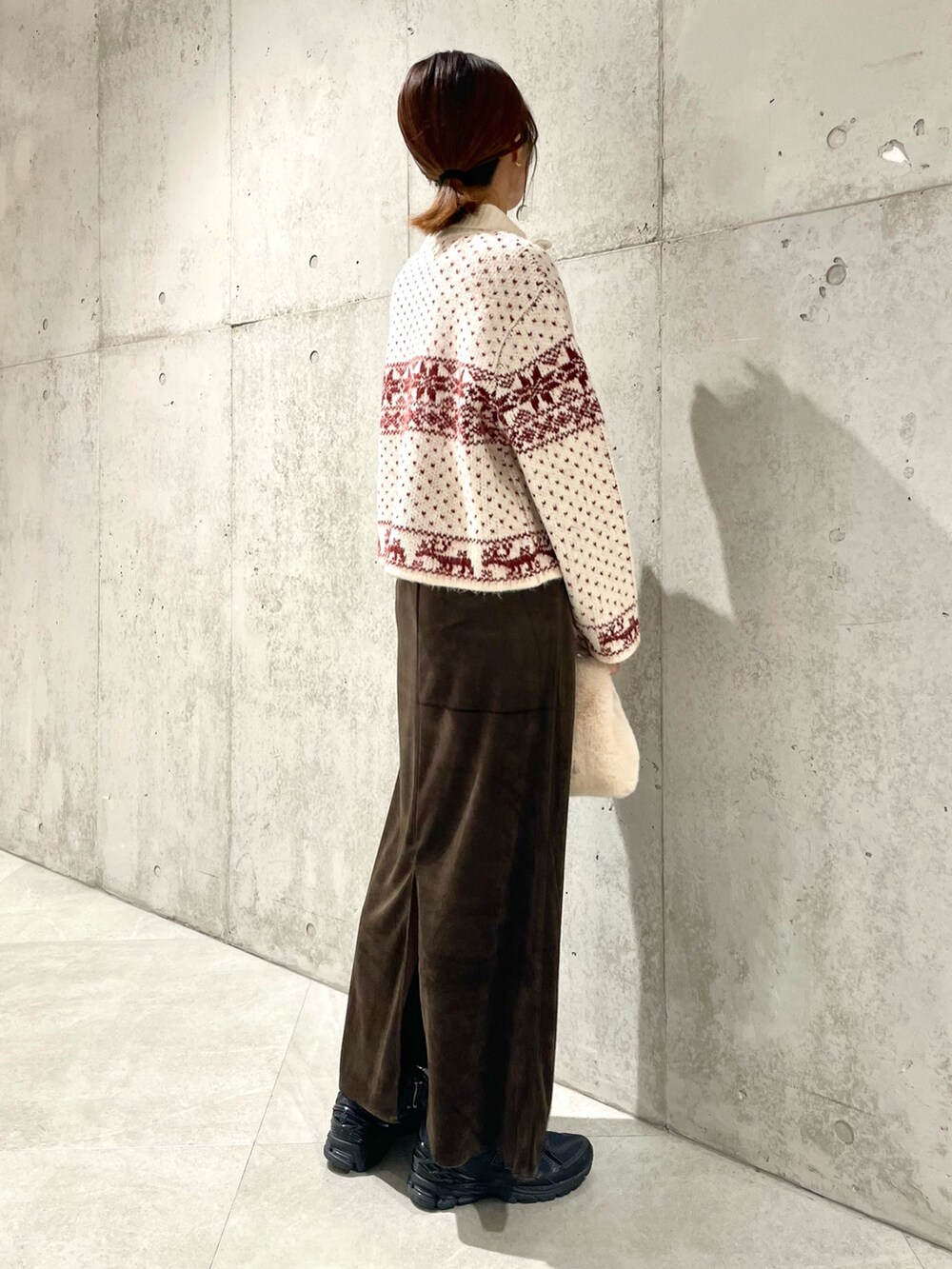 ベージュ系のハンドバッグ、ブラウン系のスカート、レッド系のニット/セーターを着用したレディースの秋コーディネートの3枚目の写真