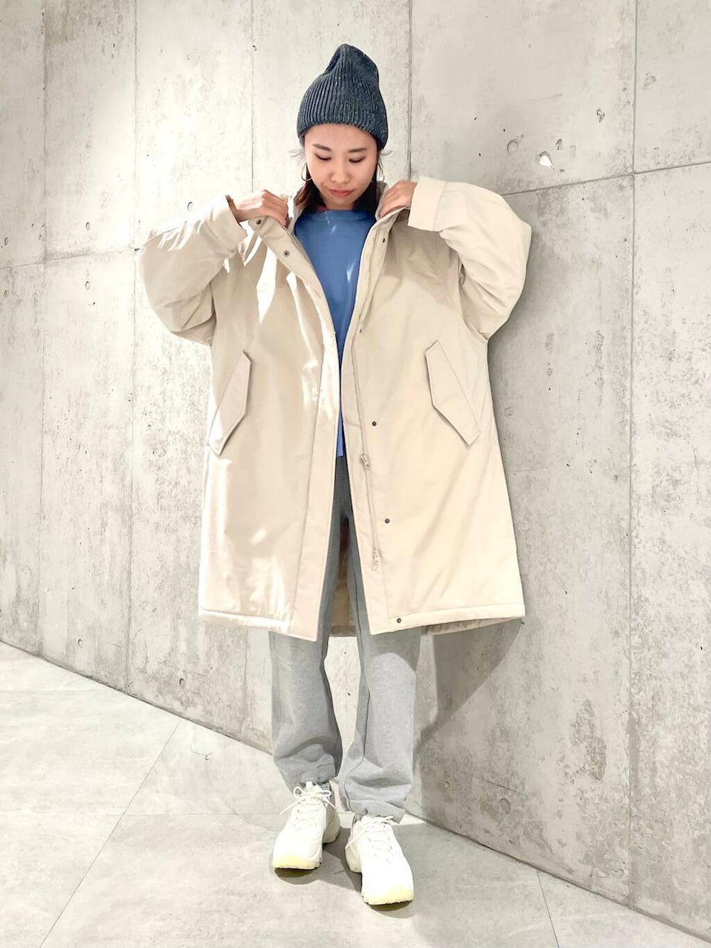 ホワイト系のスニーカー、ベージュ系のダウンジャケット/コート、ブルー系のニット/セーターを着用したレディースの冬コーディネートの2枚目の写真