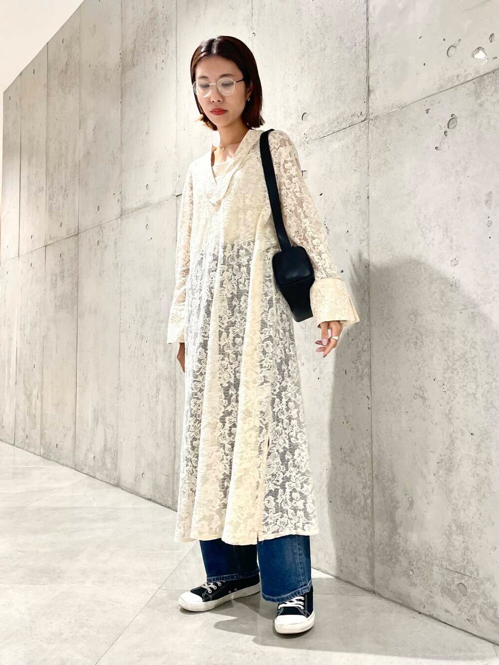 ブルー系のデニムパンツ、ブラック系のショルダーバッグ、ホワイト系のワンピースを着用したレディースの秋コーディネートの3枚目の写真